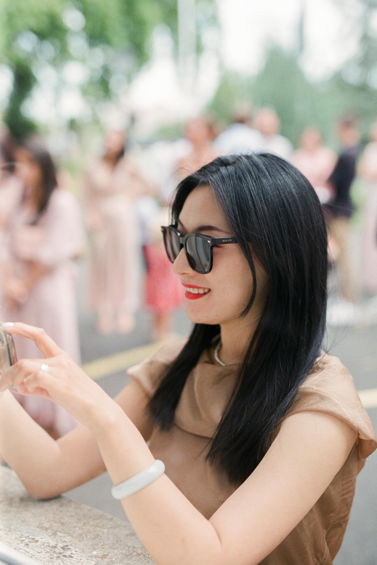 Une invitée en lunettes de soleil photographie les mariés avec son téléphone
