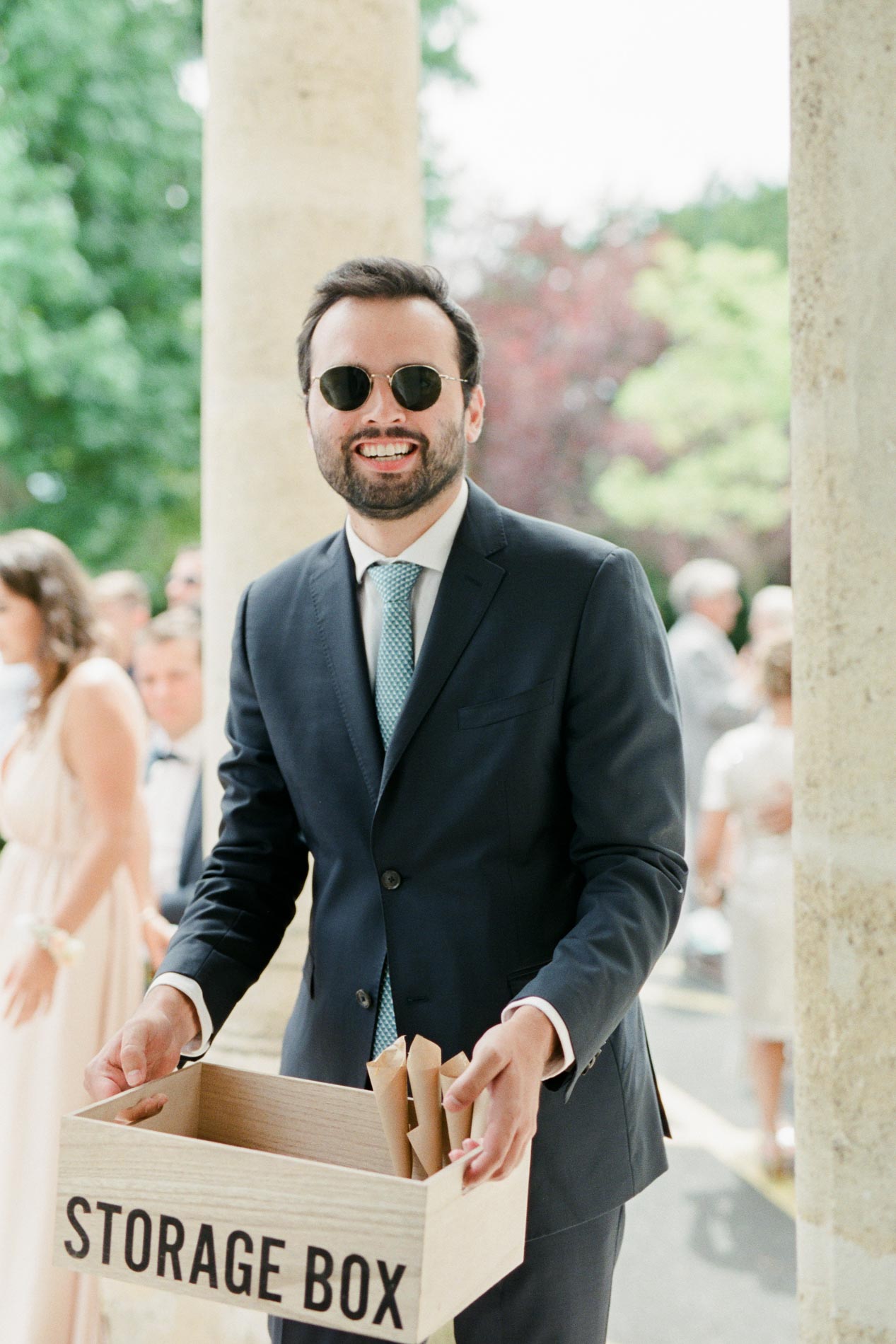 Invité souriant en lunettes de soleil tenant une boîte de cônes de confettis