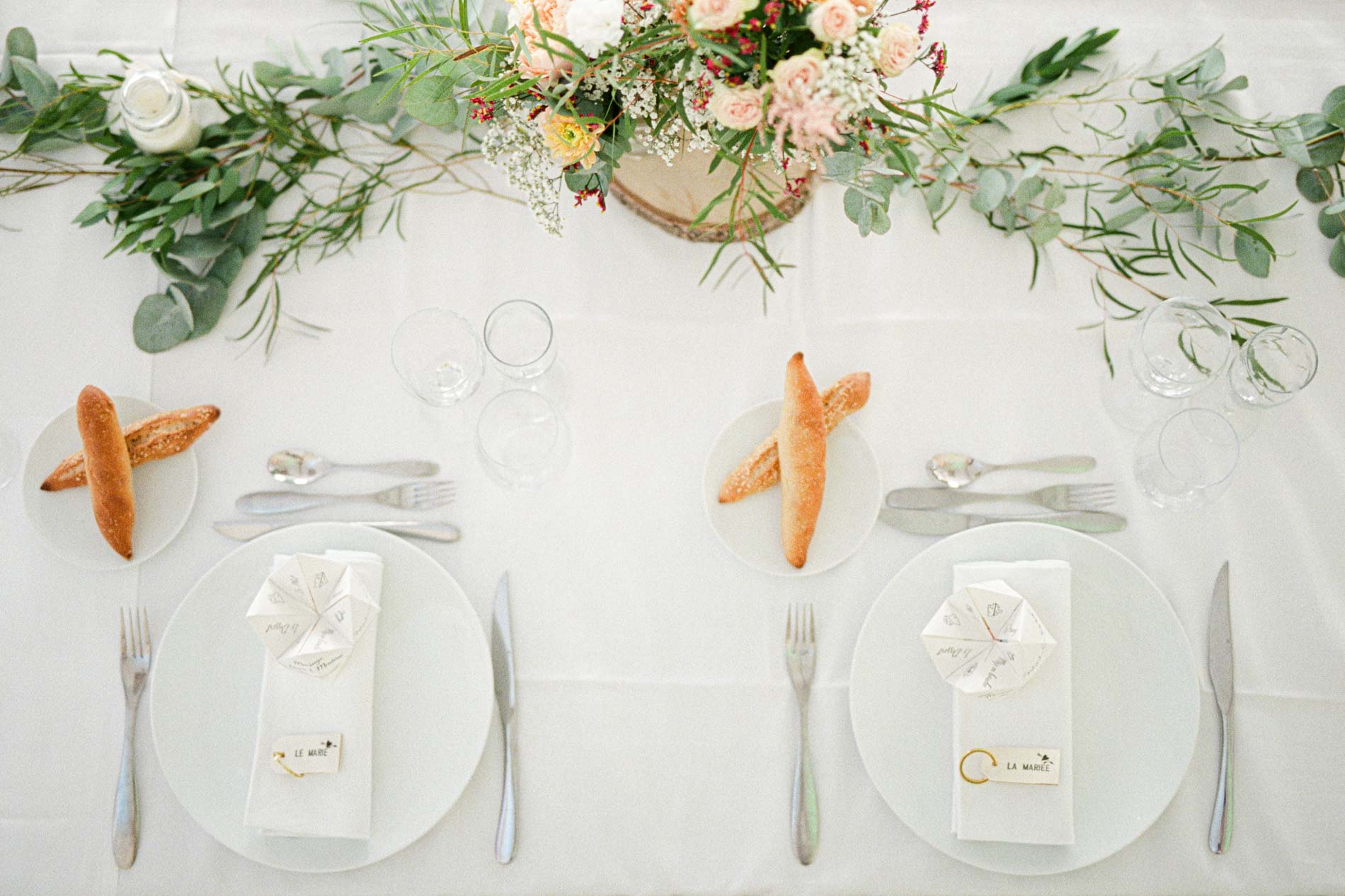 Table de mariage dressée avec guirlande d'eucalyptus et petits pains au Domaine de Larchey