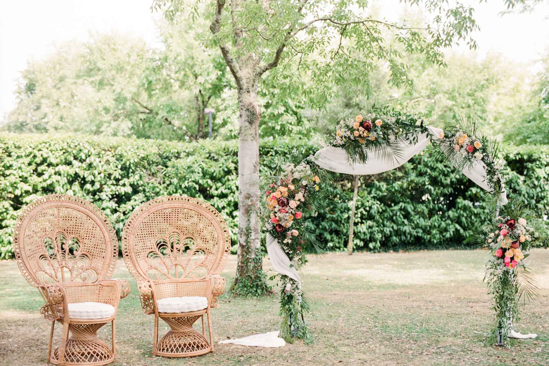 Fauteuils en rotin et arche fleurie de la cérémonie laïque au Domaine de Larchey
