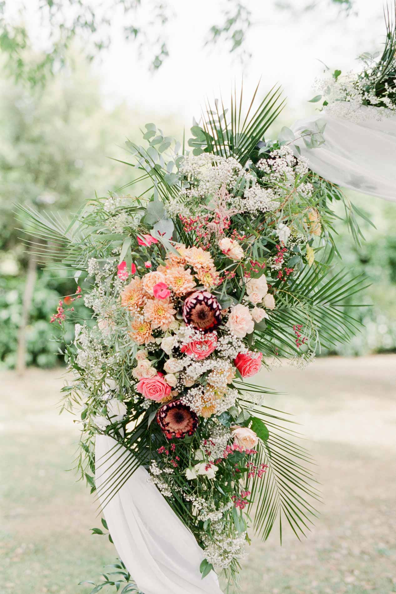 Composition florale de roses et de palmes sur un pilier de l'arche de cérémonie