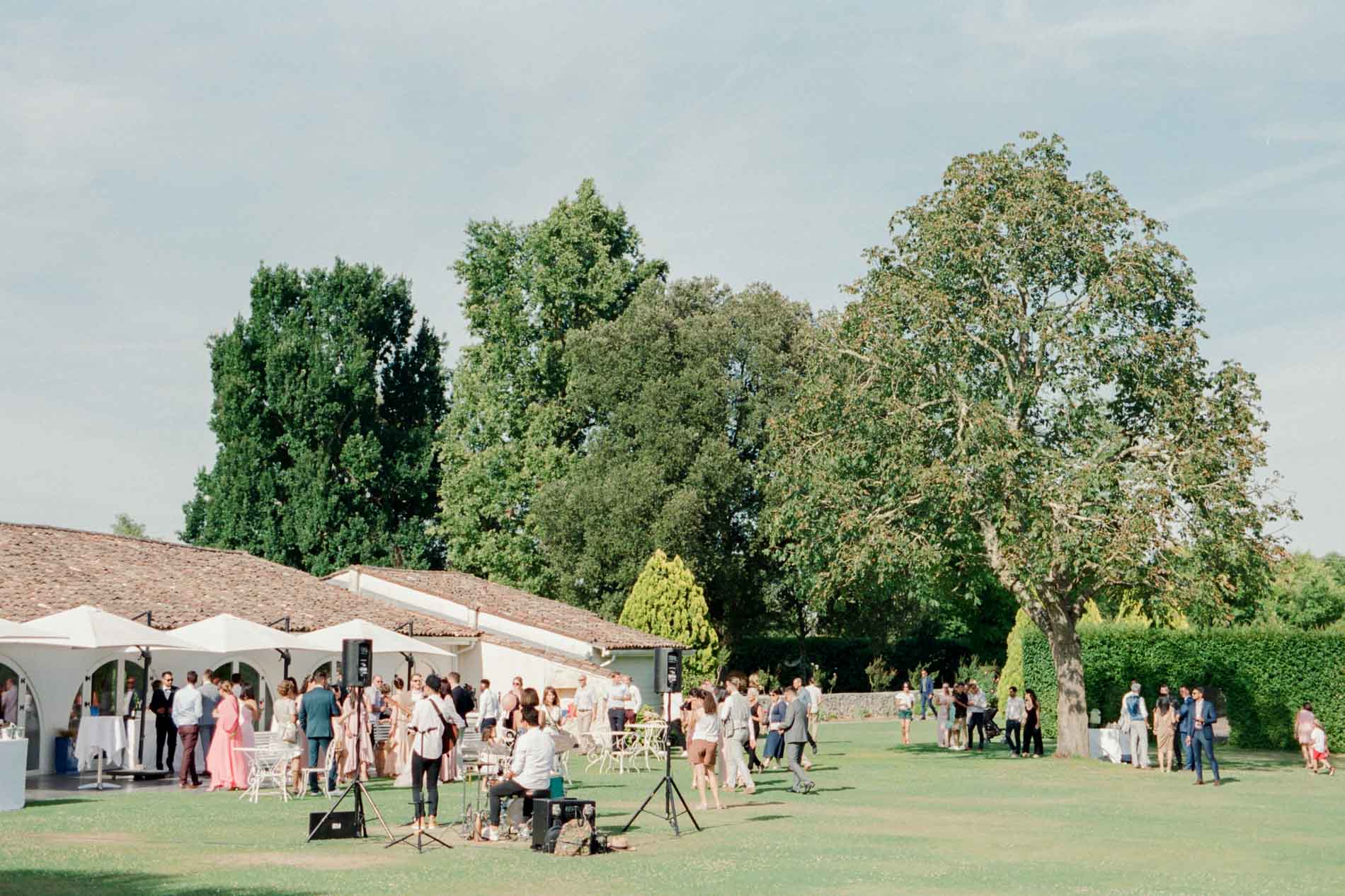 Vin d'honneur sous les arbres et les parasols sur la pelouse du domaine
