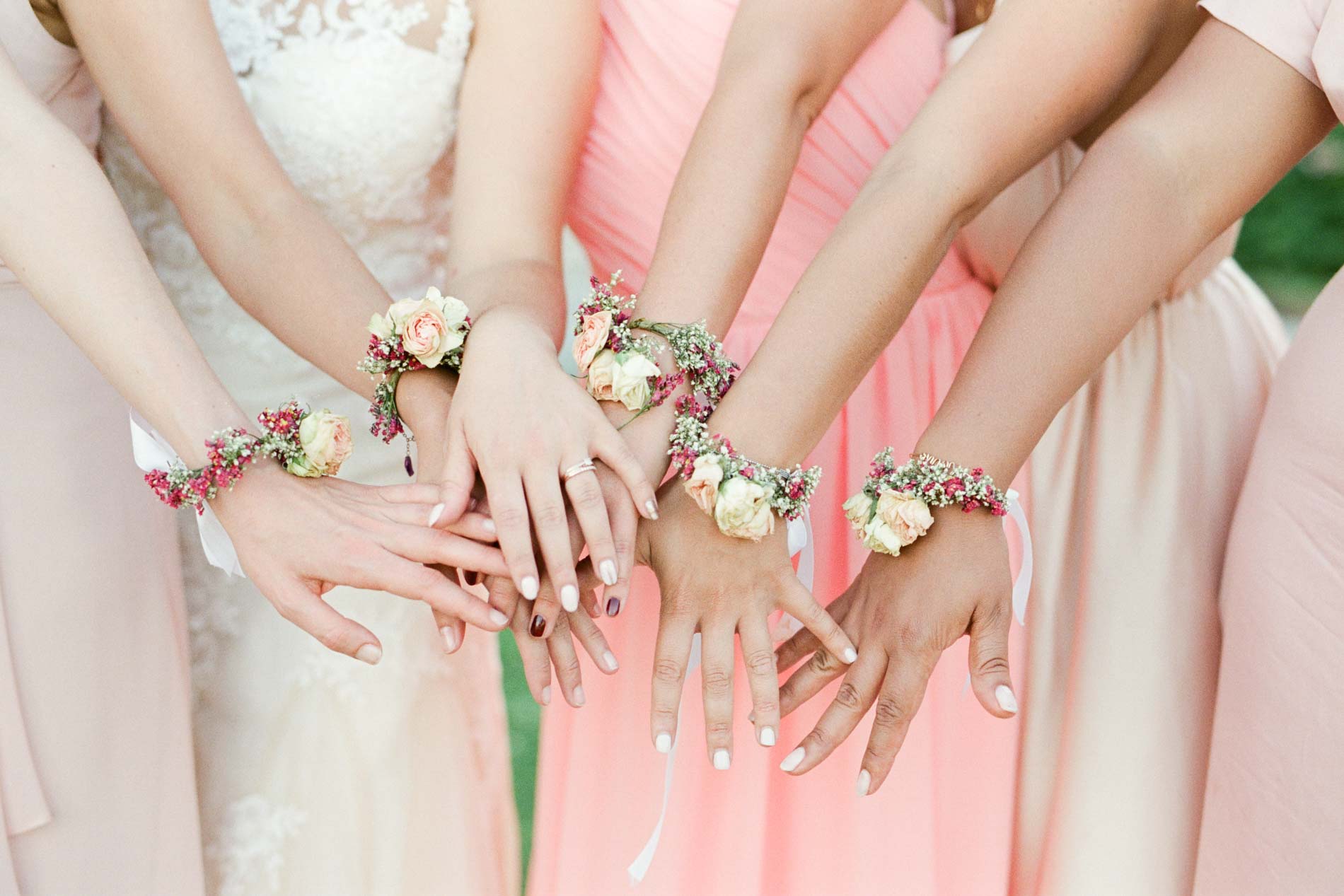 Mains de la mariée et de ses demoiselles d'honneur aux bracelets de fleurs