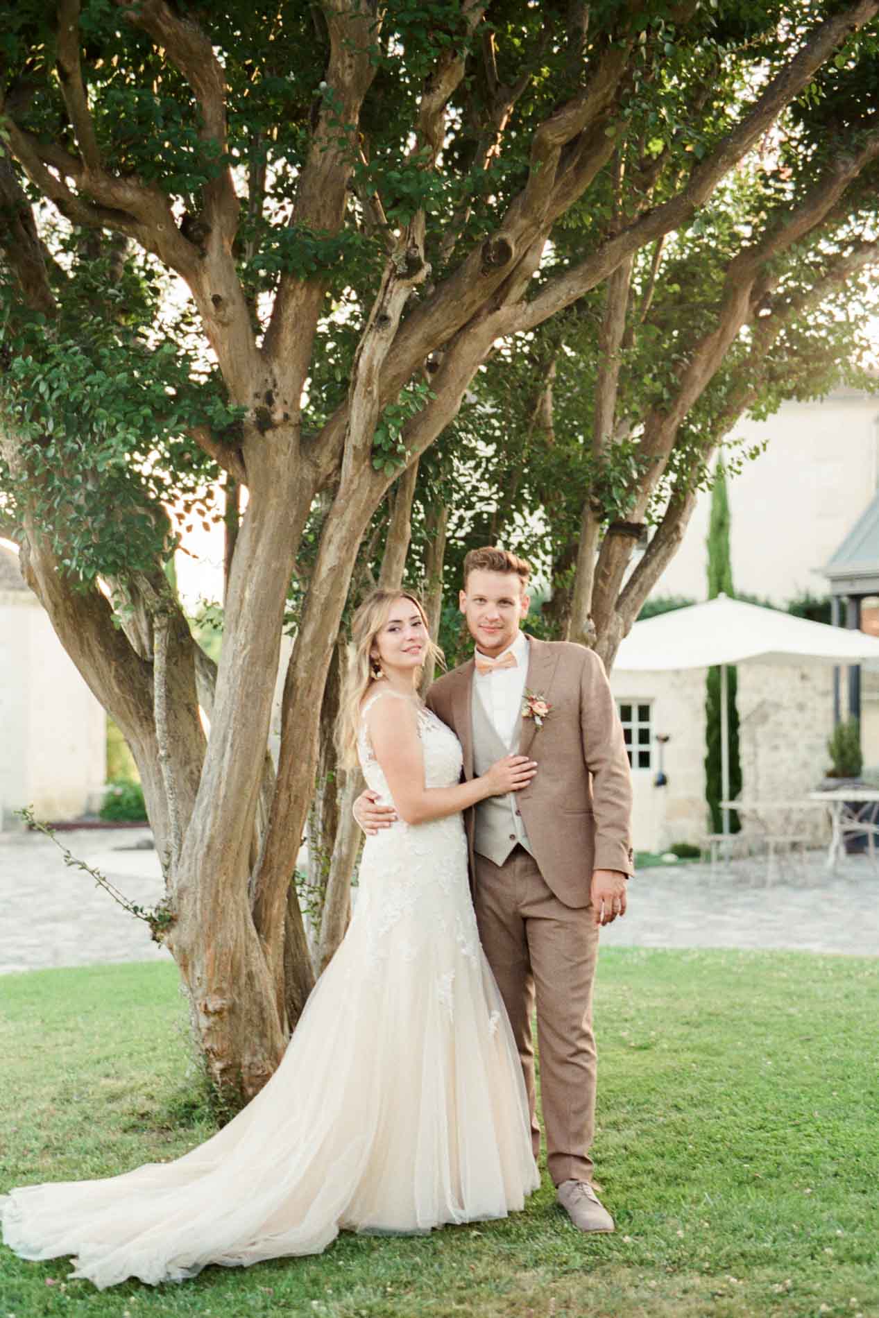 Portrait des mariés sous un grand arbre au coucher du soleil au Domaine de Larchey