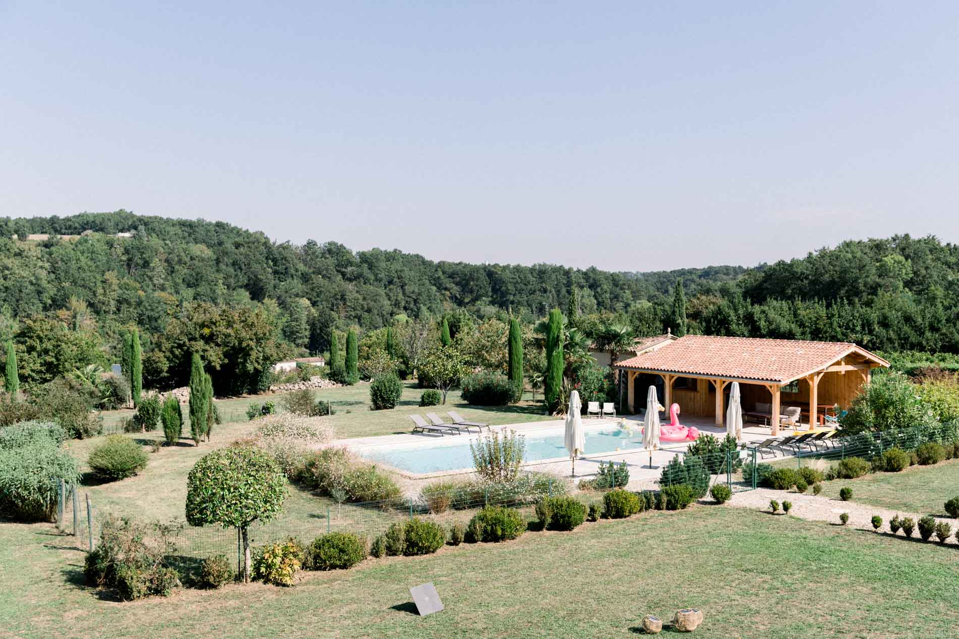 View over an estate with a pool and wooded hills, where the wedding preparations took place