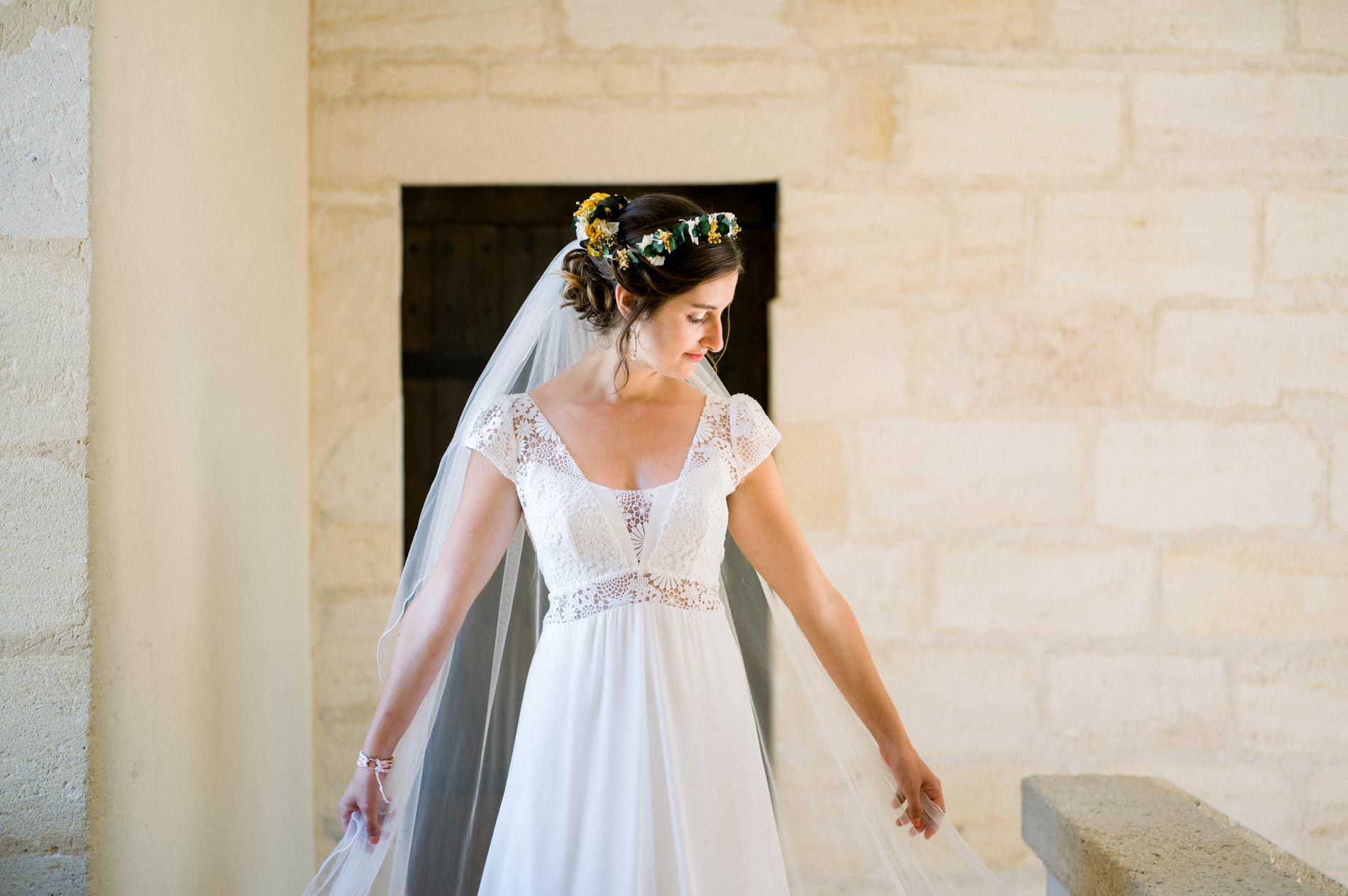 Bride spreading her veil in front of a pale stone wall