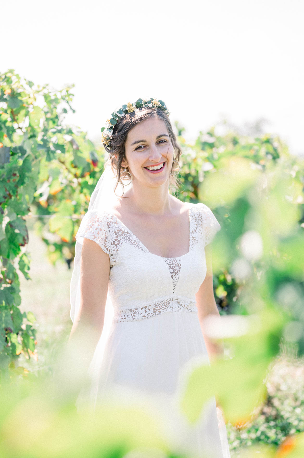 Bride laughing among the vines with a flower crown in her hair