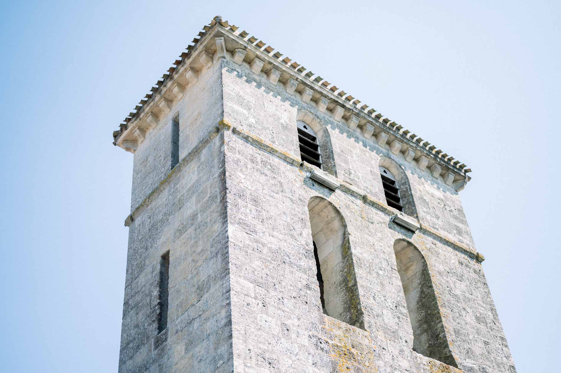 Stone bell tower of the Saint-Aubin church in Latresne against a blue sky
