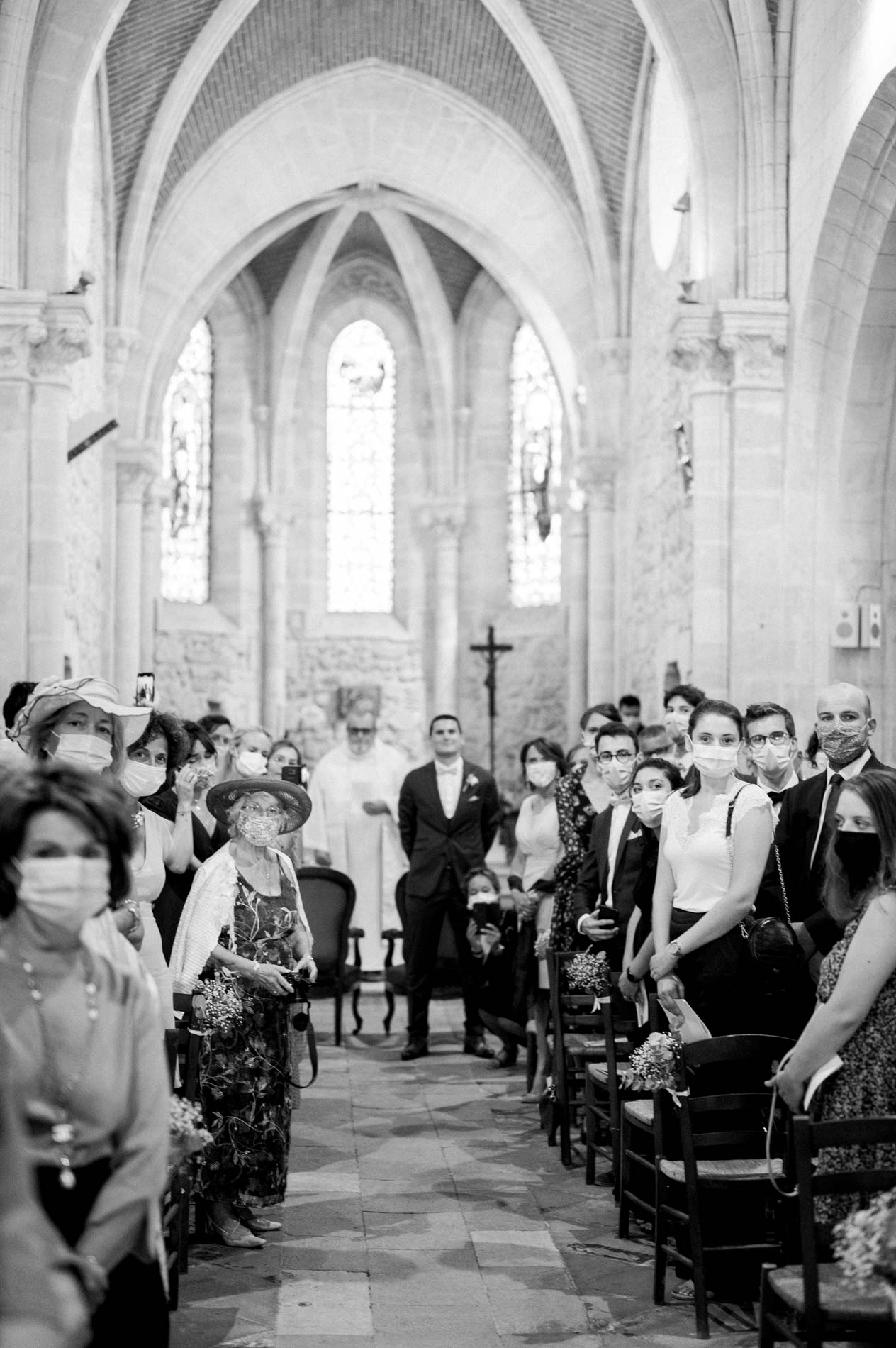 Masked guests in the nave of Saint-Aubin church in Latresne, in black and white