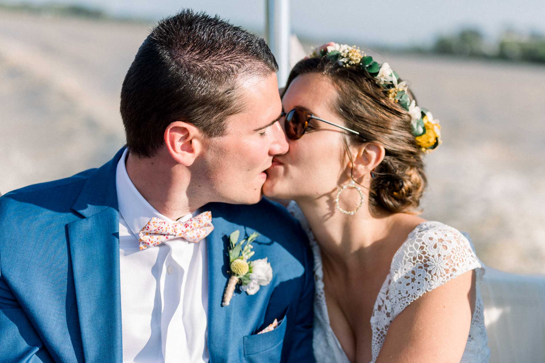 The bride and groom kissing in the sun on the boat on the Garonne