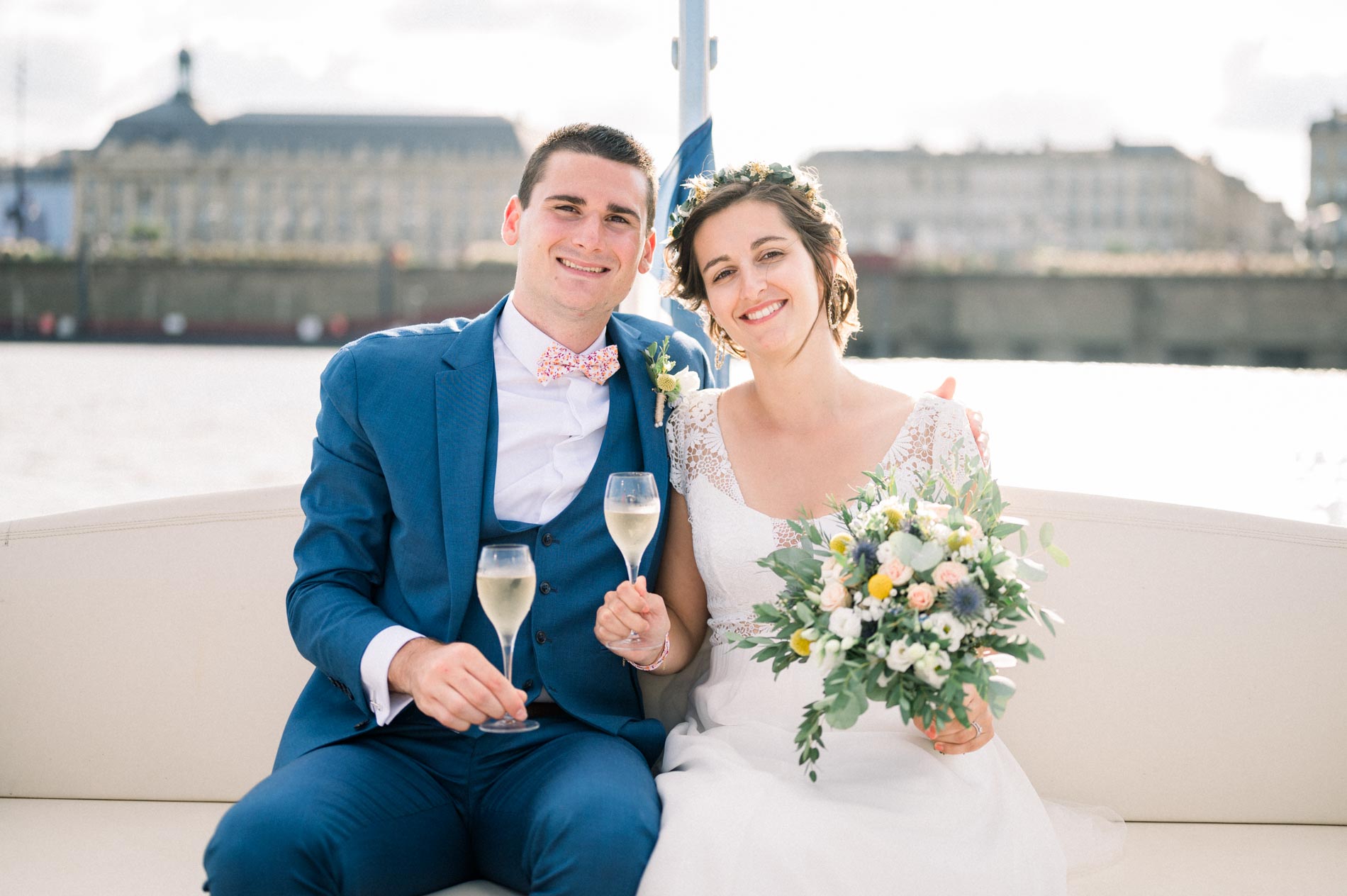 The couple seated on board with a glass, Bordeaux's riverside quays behind them