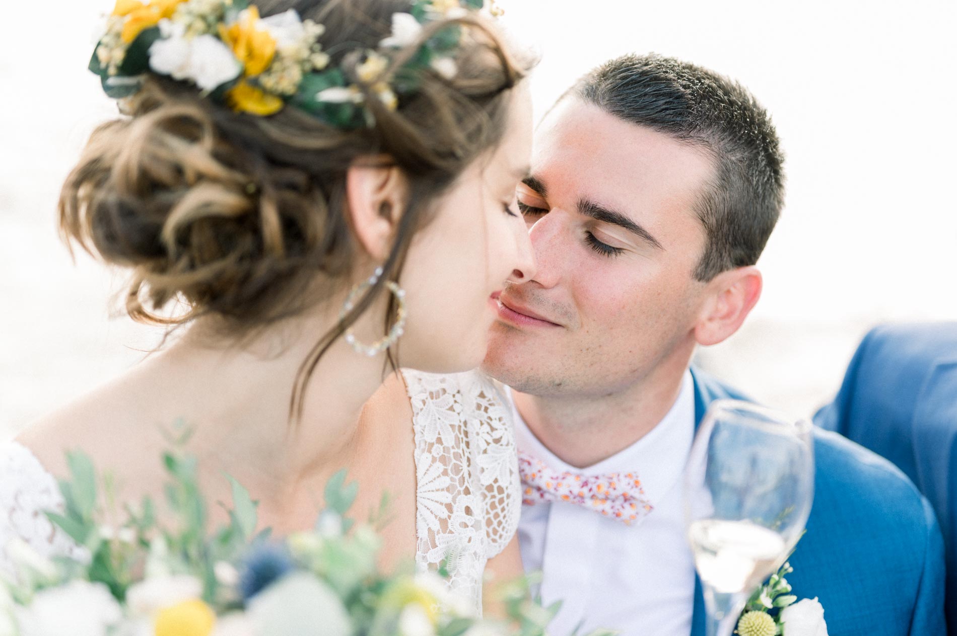 A kiss on the bride's cheek on board the boat, flower crown in her hair
