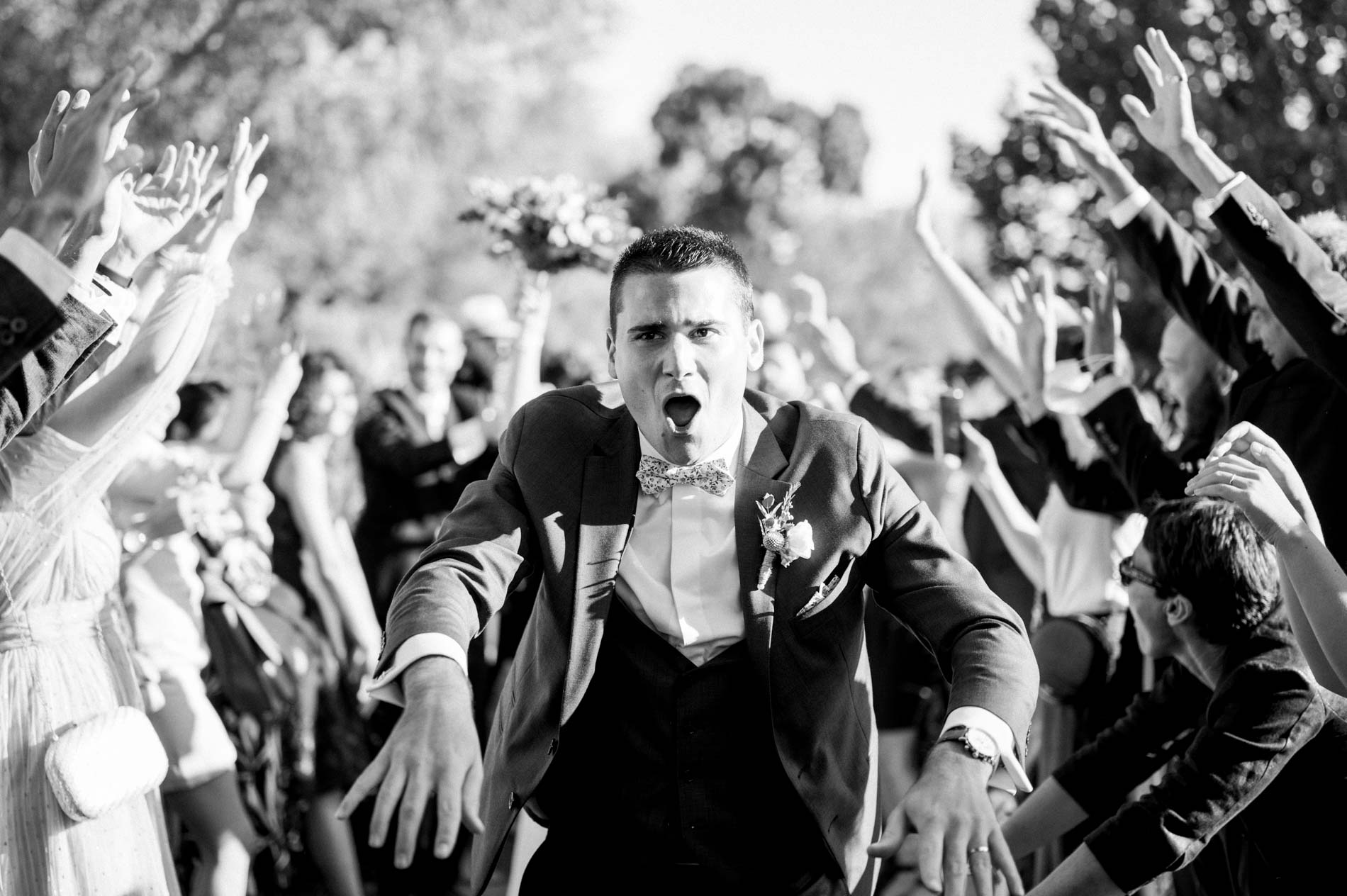 Groom cheered on by the guests, in black and white