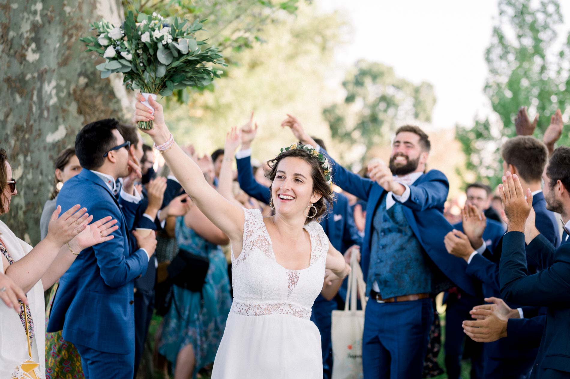 Bride raising her bouquet among celebrating guests