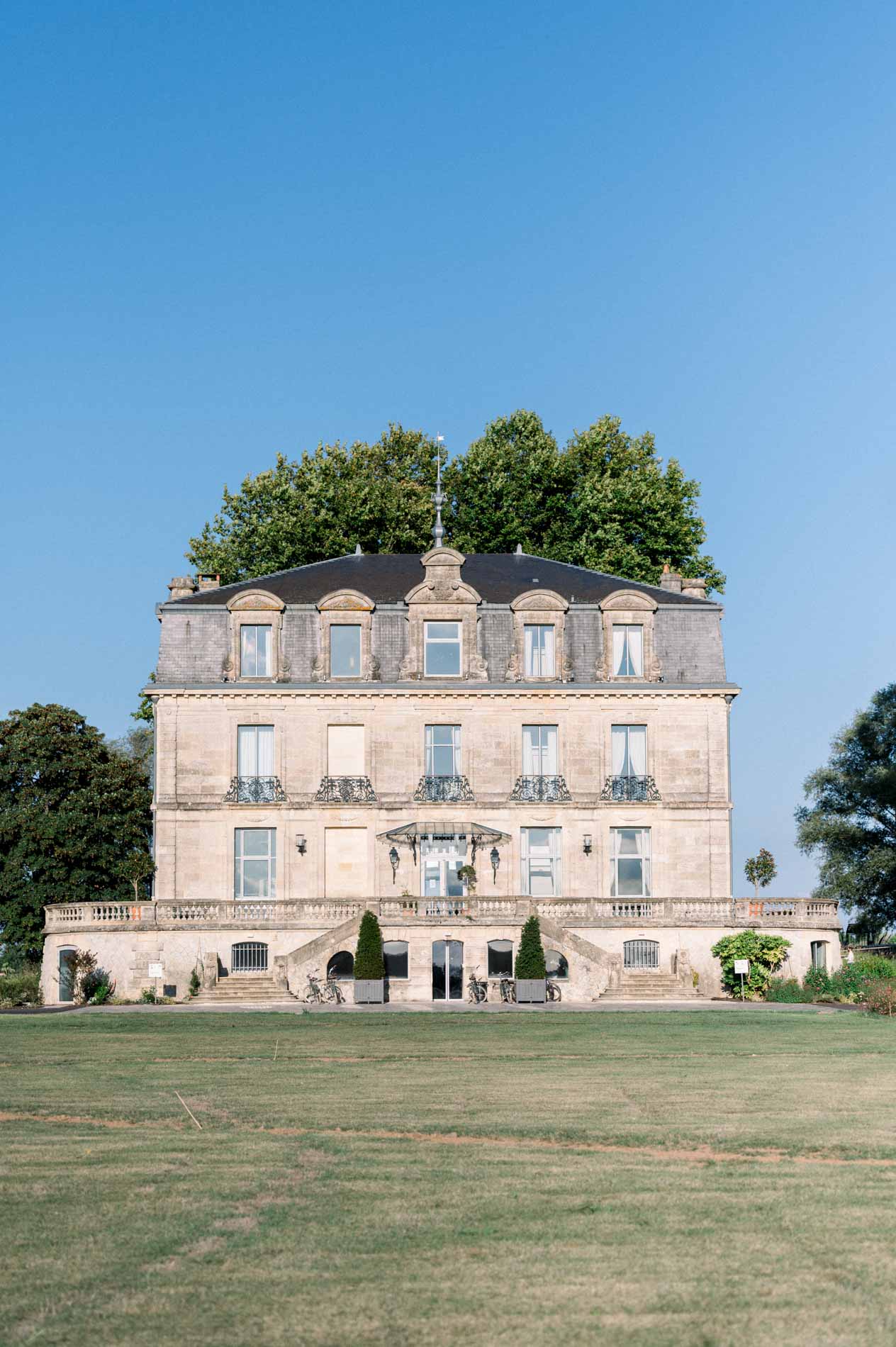 Façade of Château Grattequina under a blue sky by the Garonne