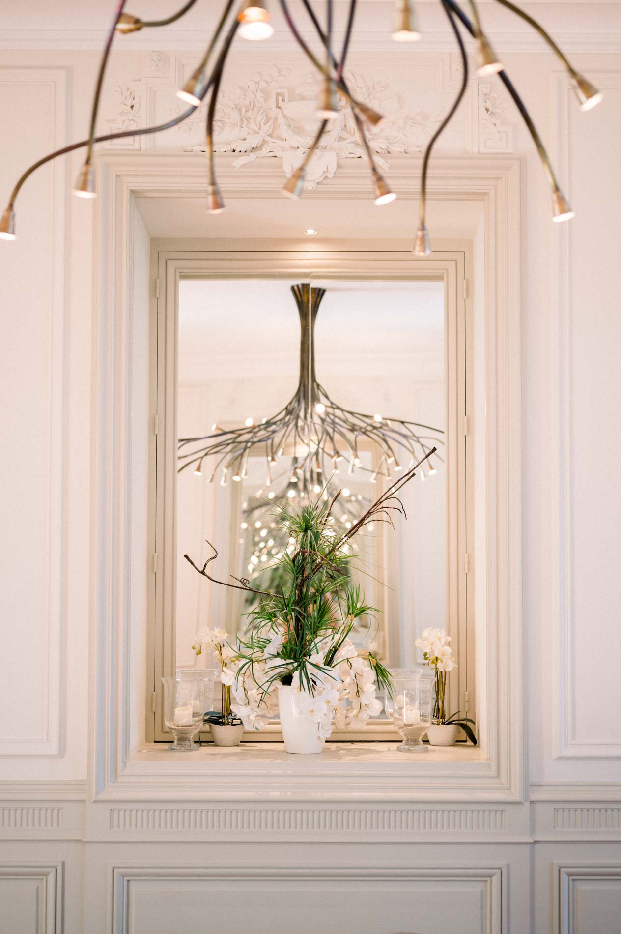 Chandelier and gilded mirror in a white reception room at Château Grattequina