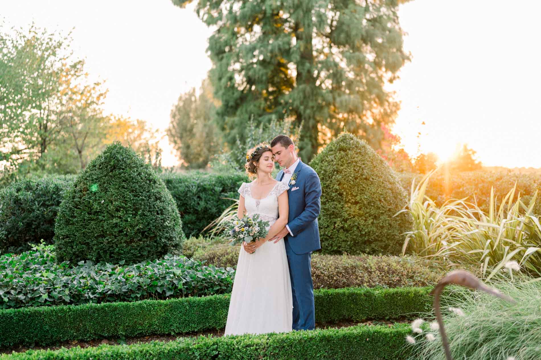 Charlotte and Aymeric embracing at sunset in the gardens of Château Grattequina