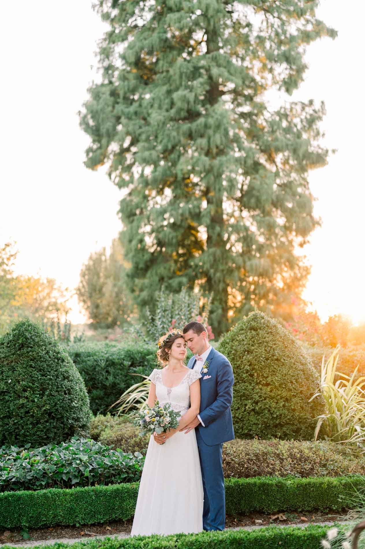 The couple embracing among clipped box hedges in the formal garden