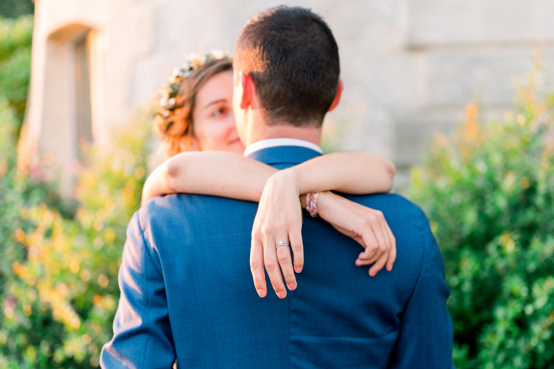 Bride with her arms around the groom's neck in the late afternoon light