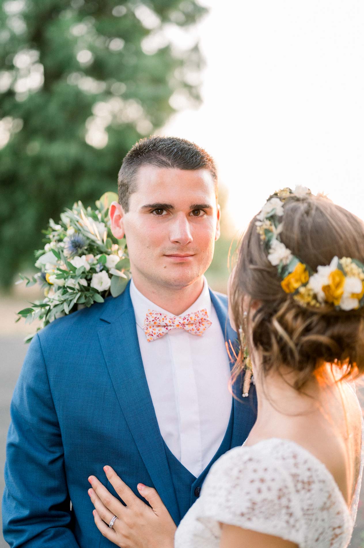 Groom in a pink bow tie holding the bride close