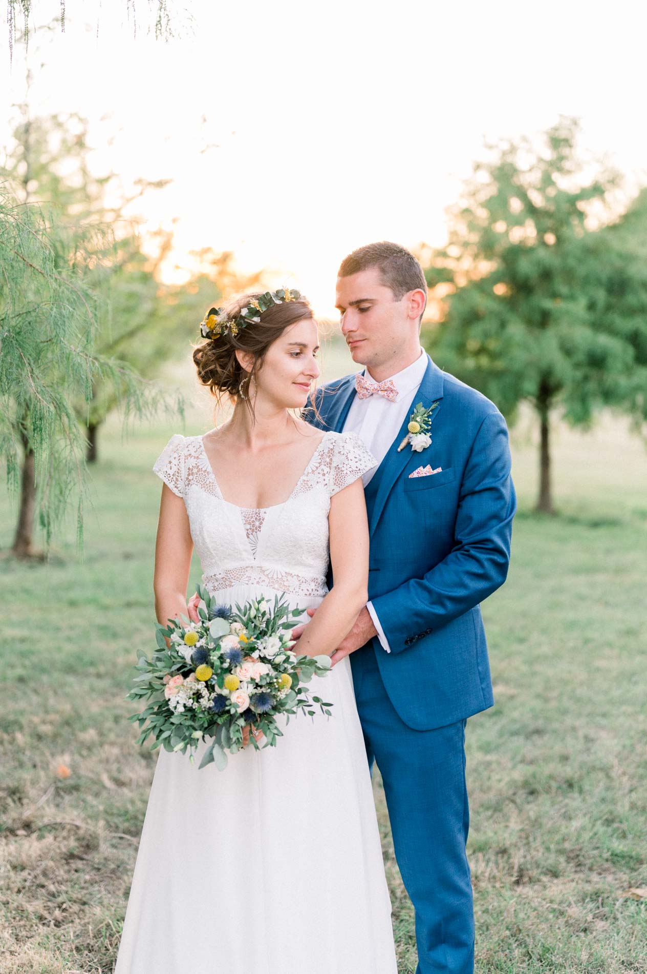The couple posing on the grass in the park, bouquet in hand