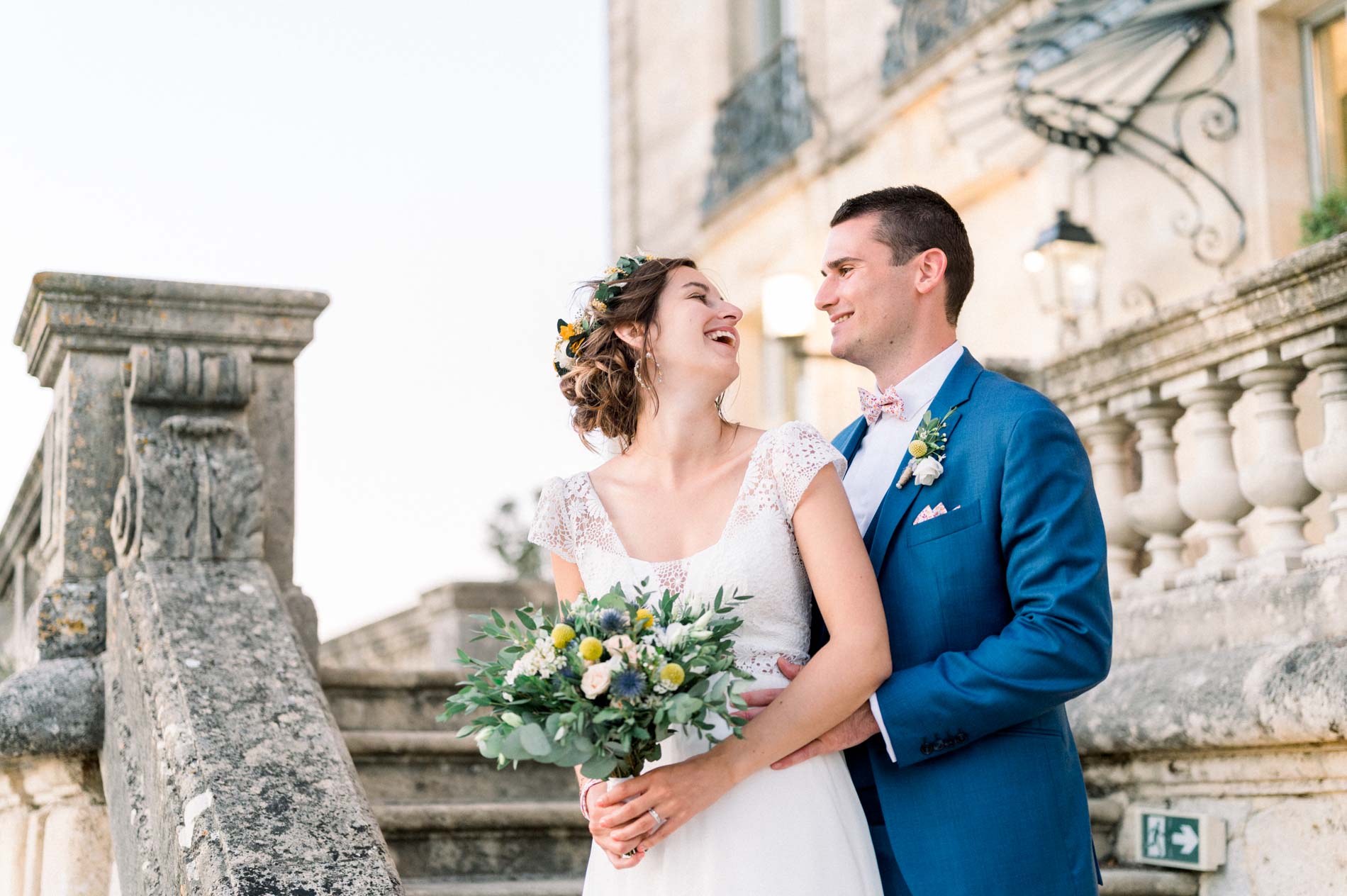 The couple laughing by the château's stone balustrade