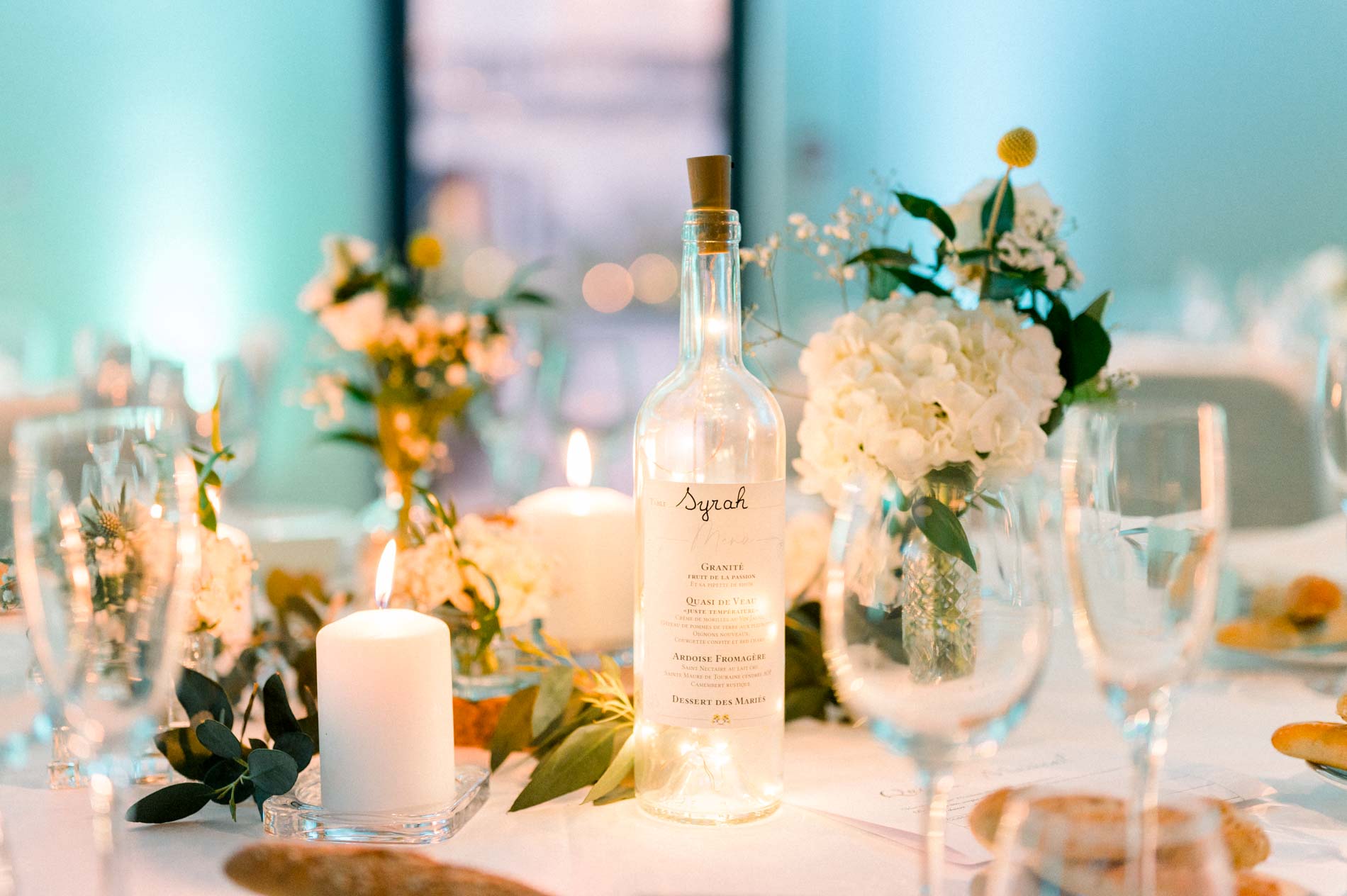 Table detail with a bottle, glasses, candle and white hydrangeas