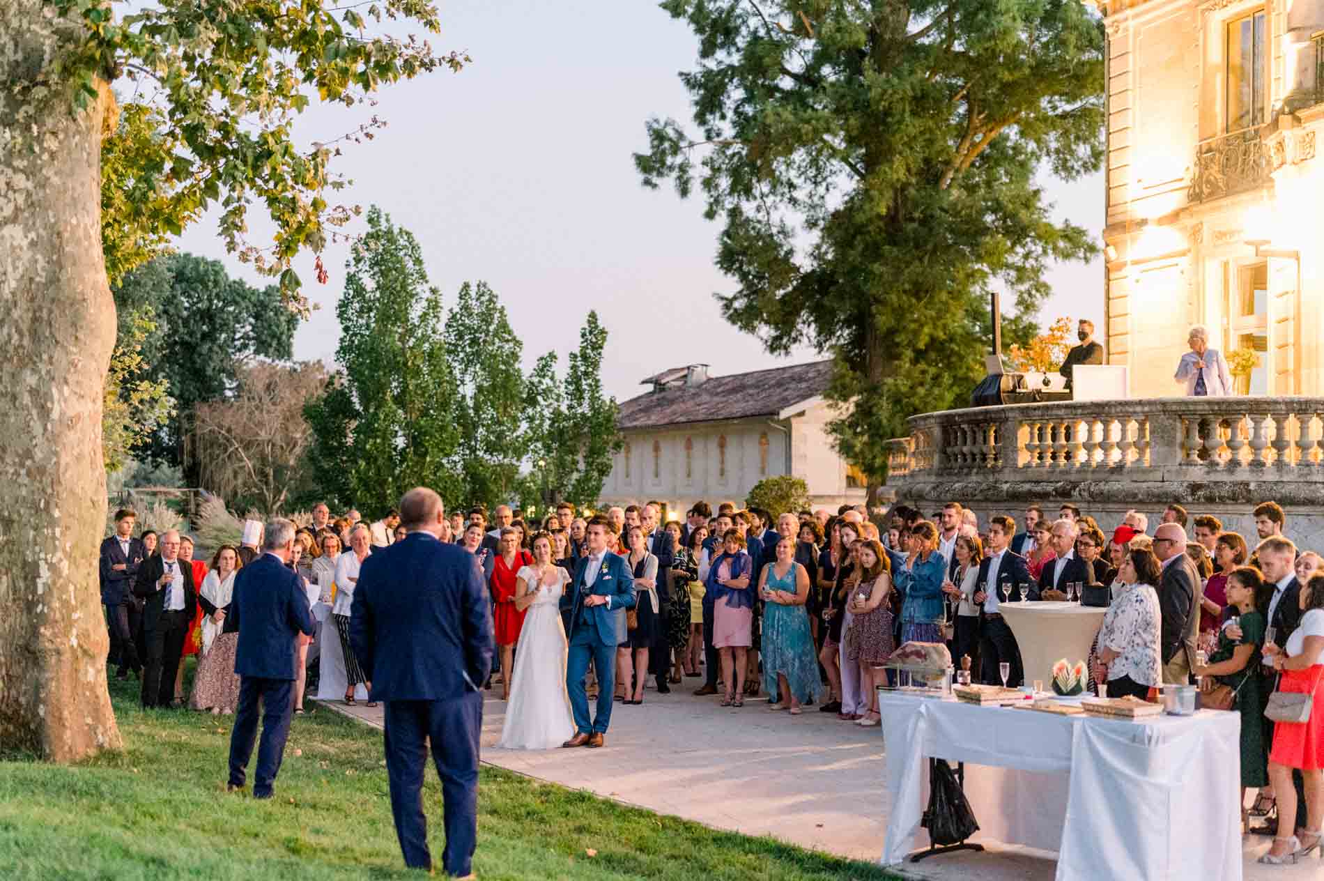 The couple facing the guests for the speeches on the château terrace