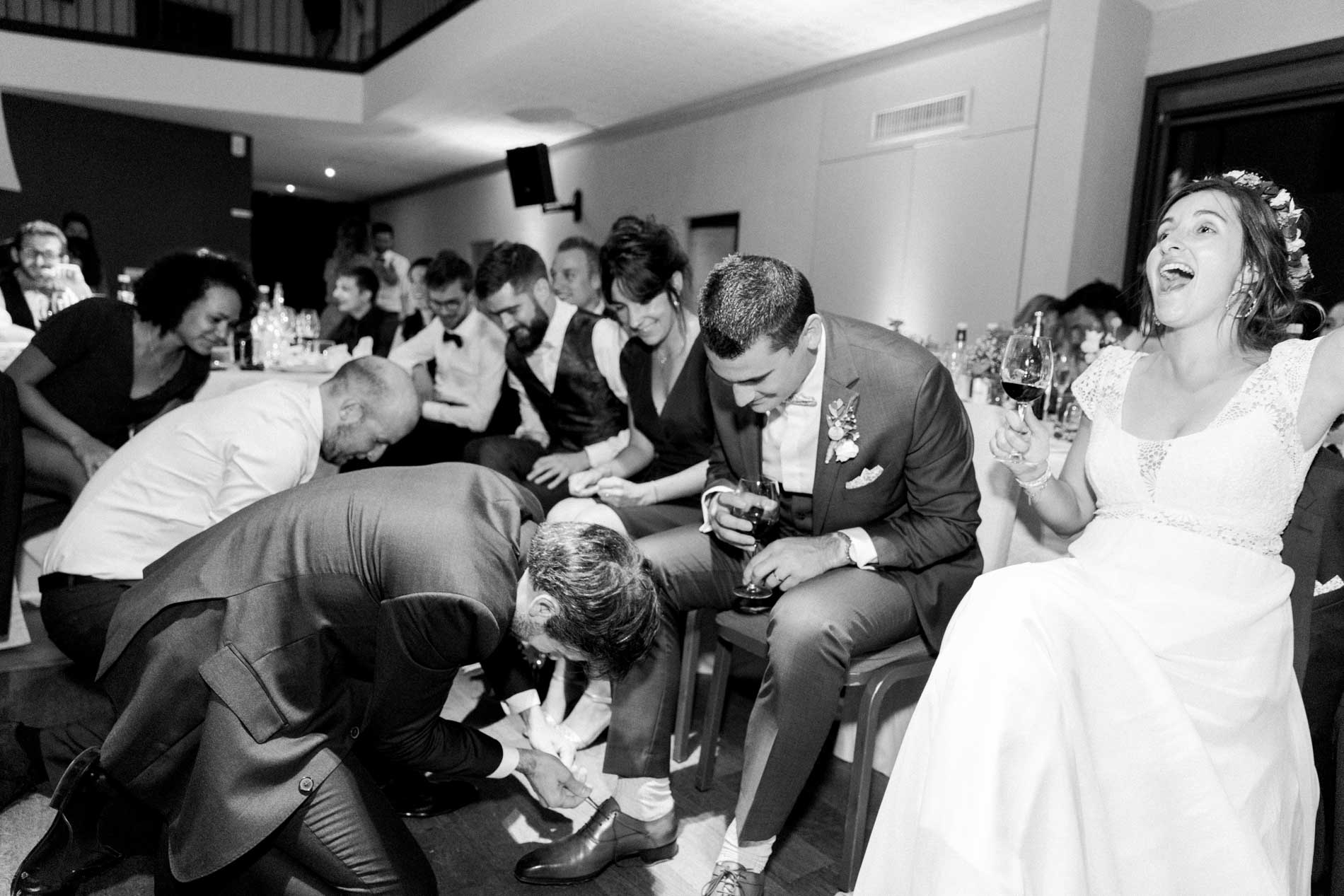Guests playing a game with the couple during dinner, in black and white