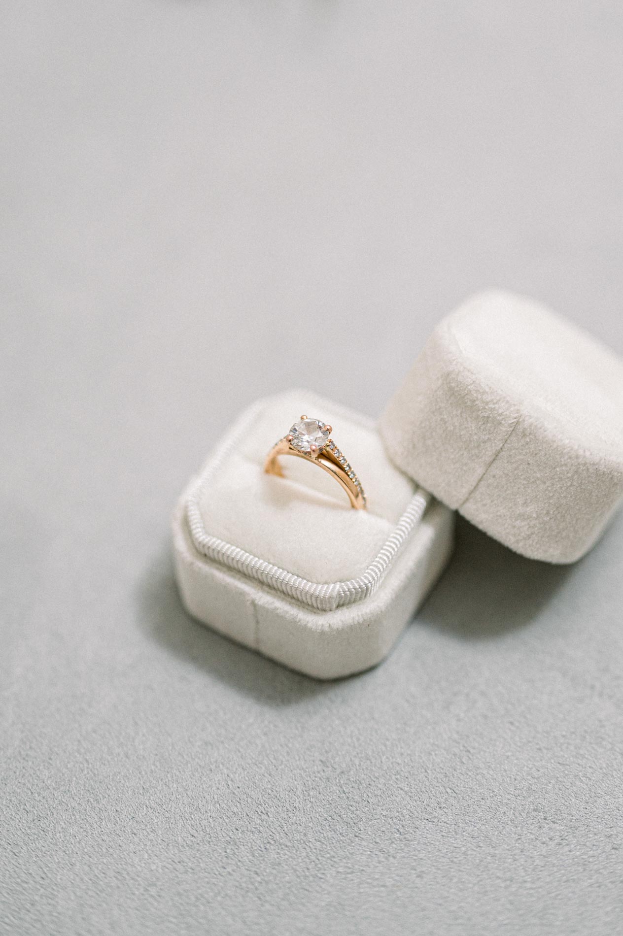 Gold engagement ring resting on a white velvet ring box