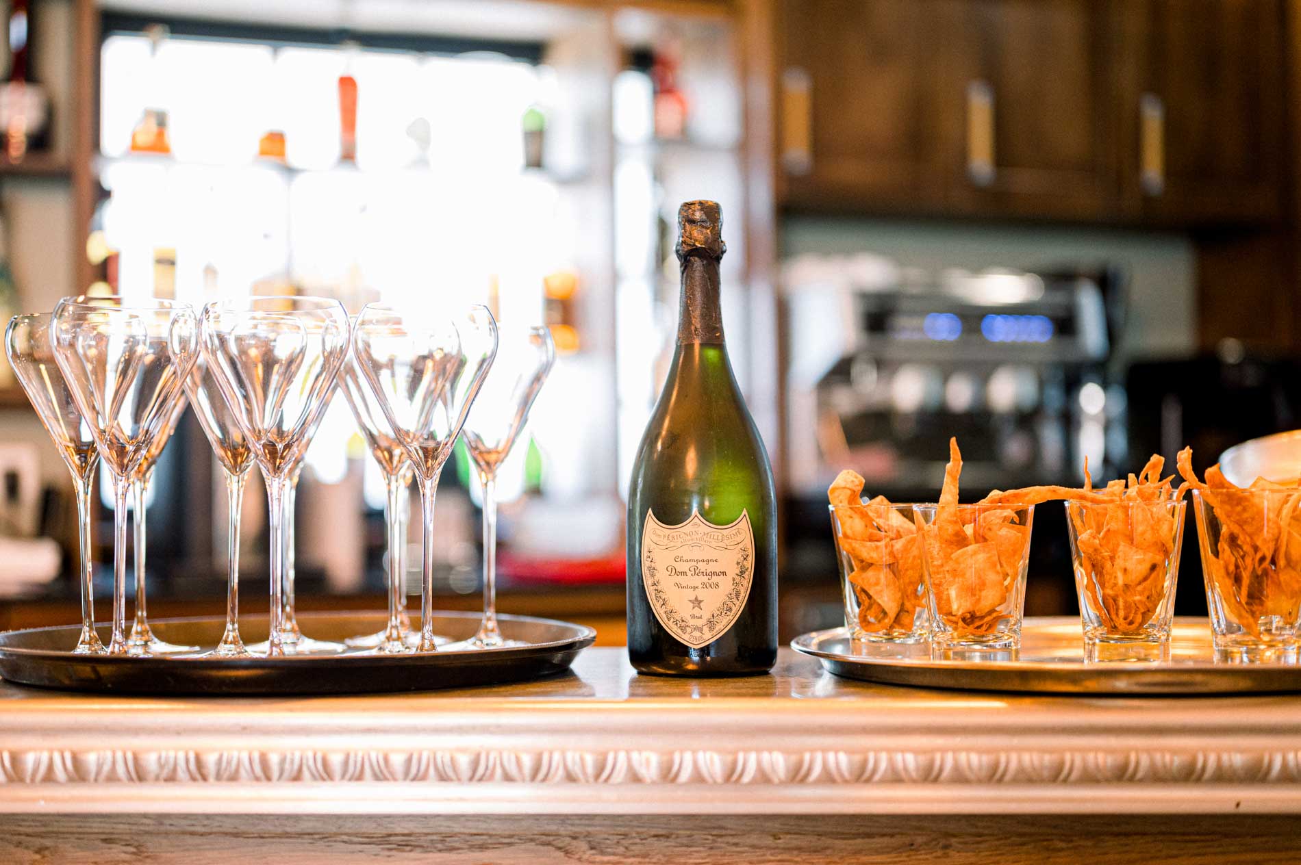 Champagne coupes and a bottle of champagne on the bar during preparations at Domaine de Larchey