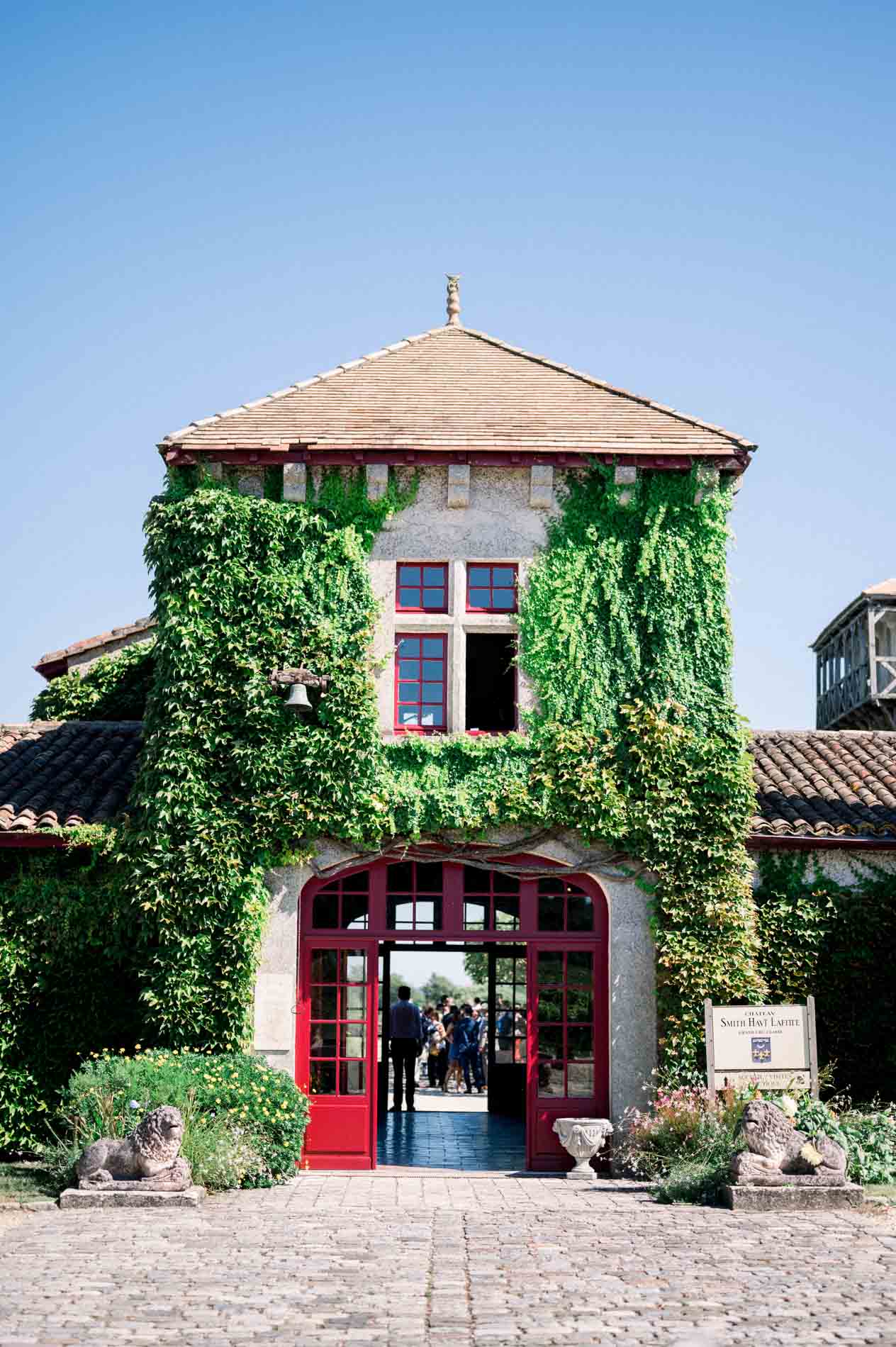 Ivy-covered building with red doors at Château Smith Haut Lafitte
