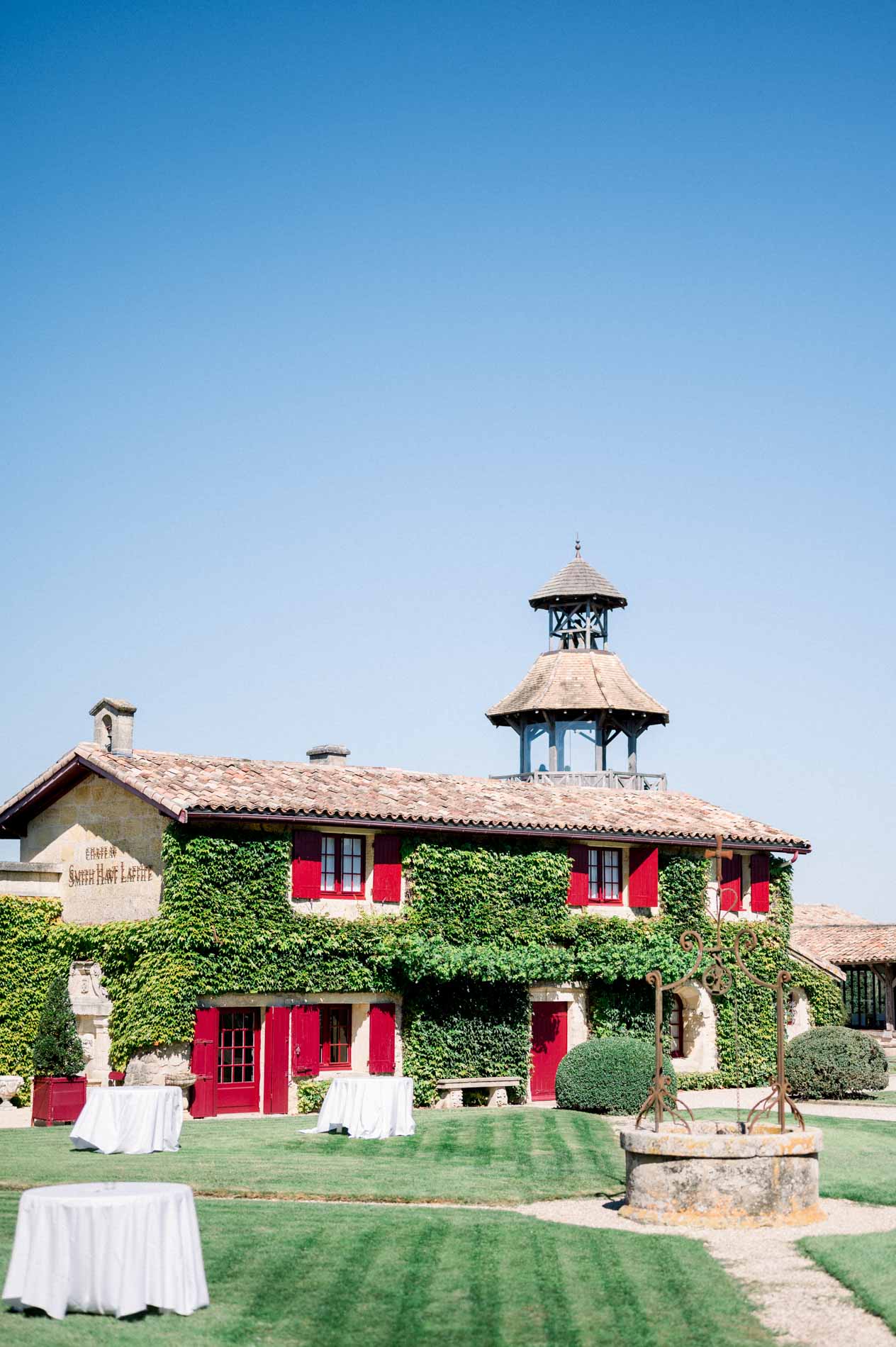 Belvedere tower and red-shuttered building of Château Smith Haut Lafitte under a blue sky