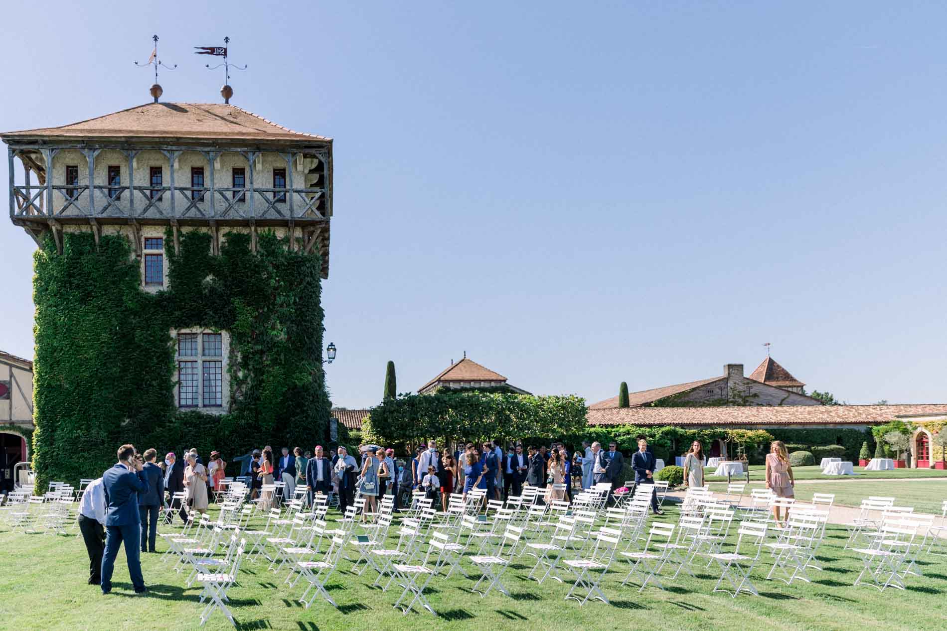 Guests taking their seats for the ceremony on the lawn beside the ivy-clad tower
