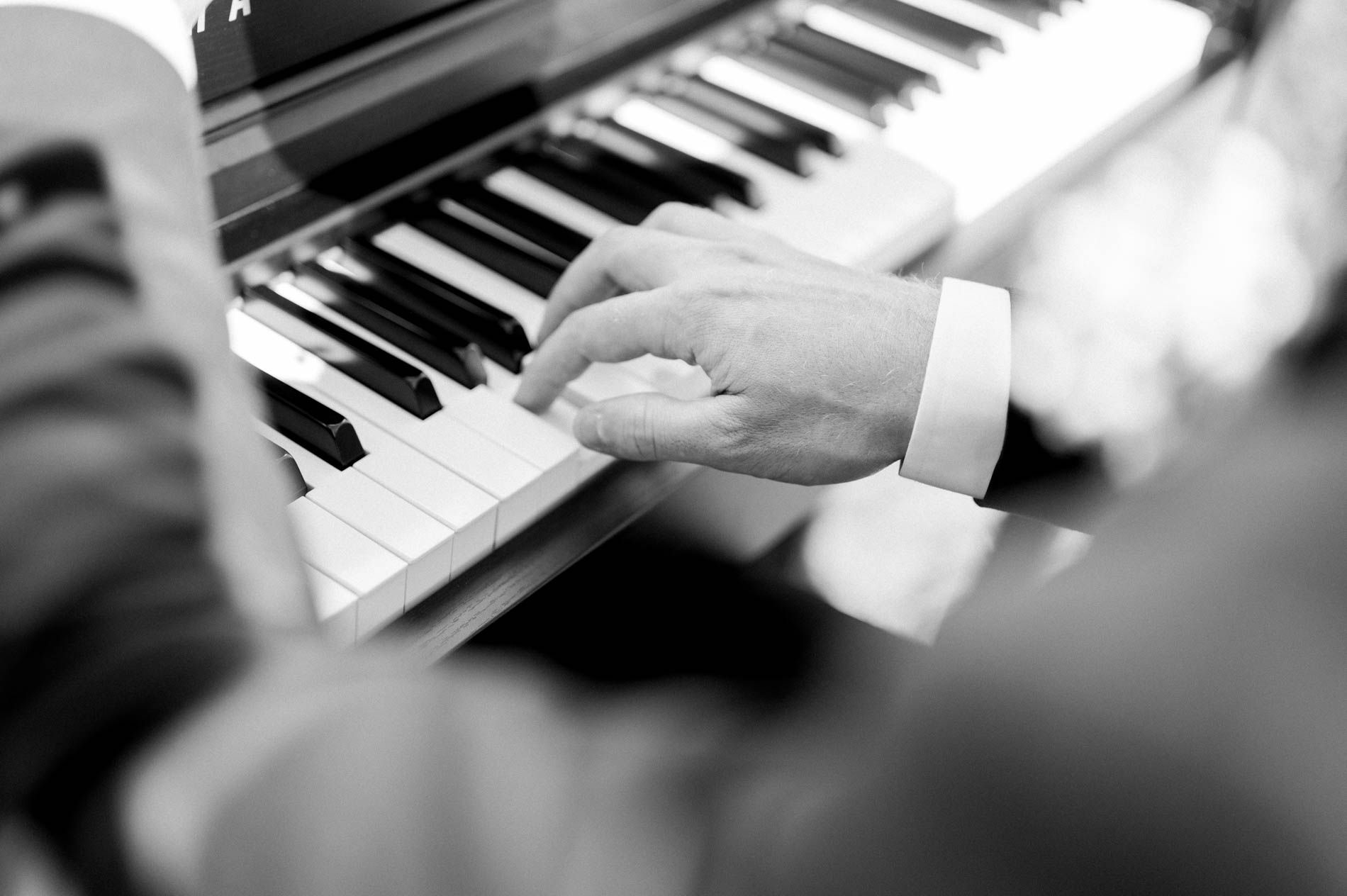 Black and white close-up of a pianist's hands on the keys during the ceremony