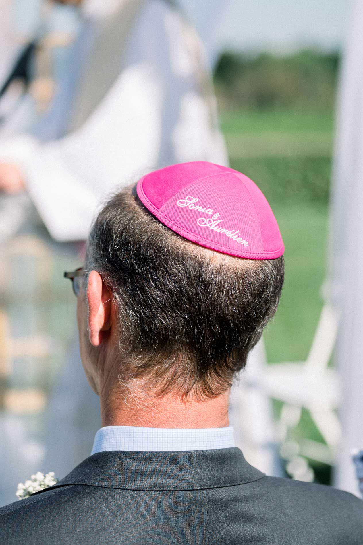Wedding guest seen from behind wearing an embroidered pink kippah