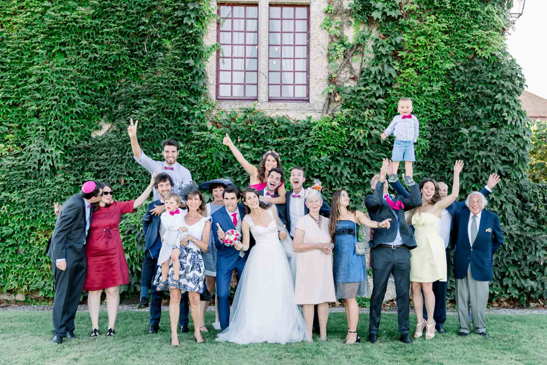 Group photo of cheering guests raising their arms in front of an ivy wall