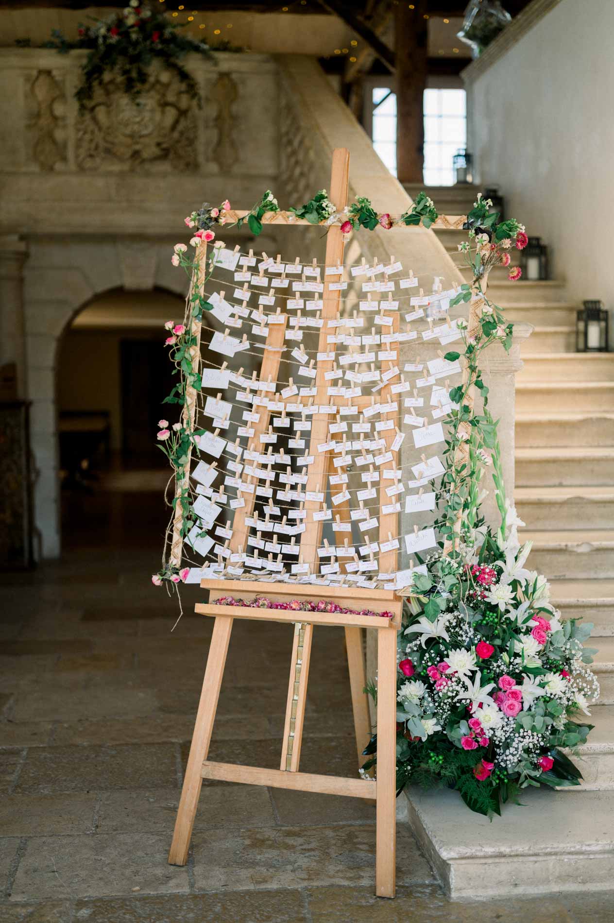 Seating chart decorated with roses on an easel at the foot of a stone staircase