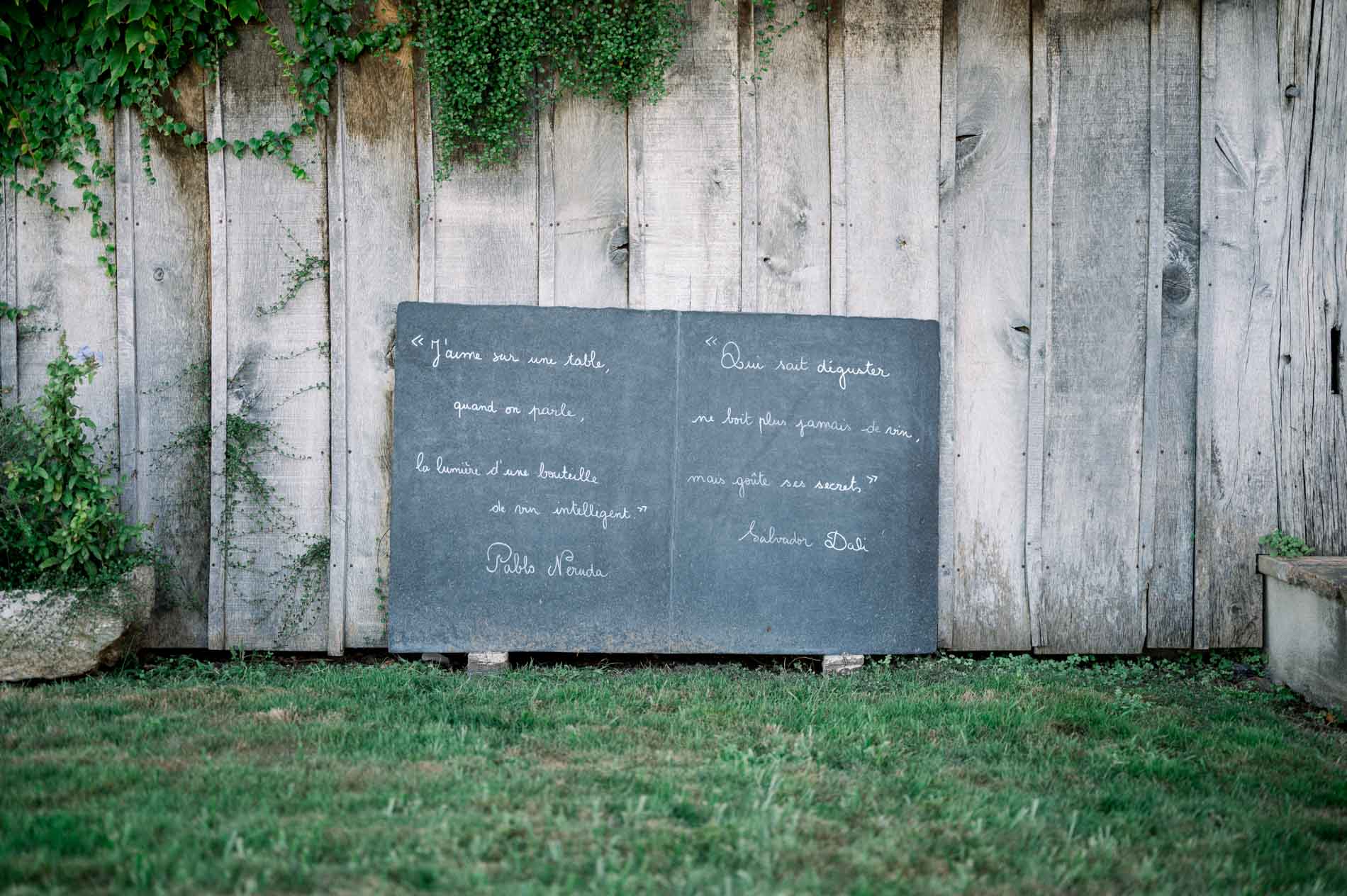 Handwritten chalkboard hanging on a weathered wooden wall at the reception