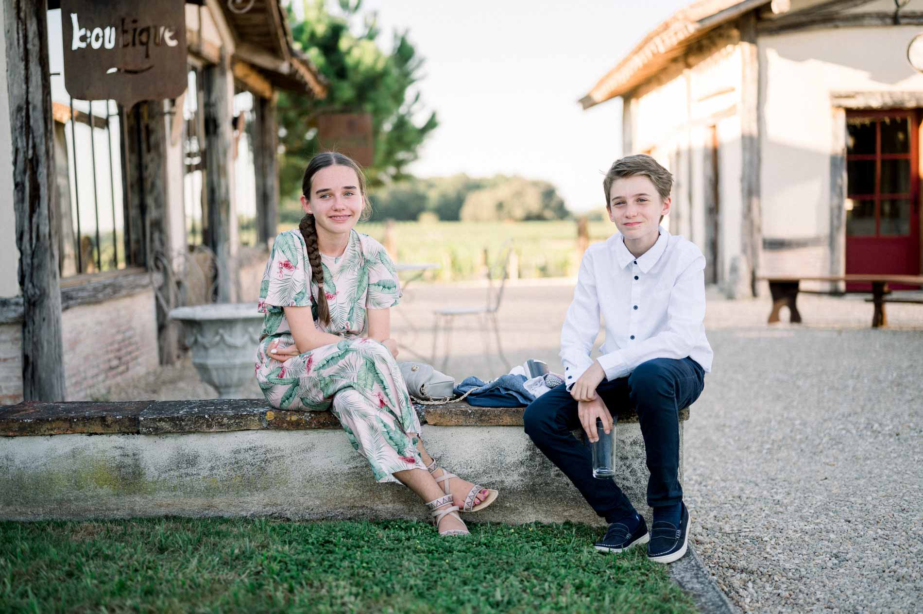 Two young guests sitting on a stone ledge during the cocktail hour