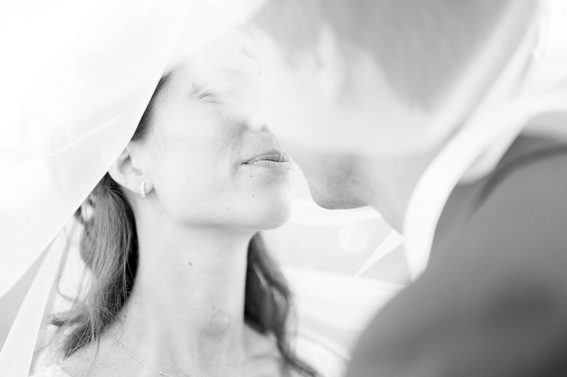 Black and white portrait of the couple forehead to forehead under the veil