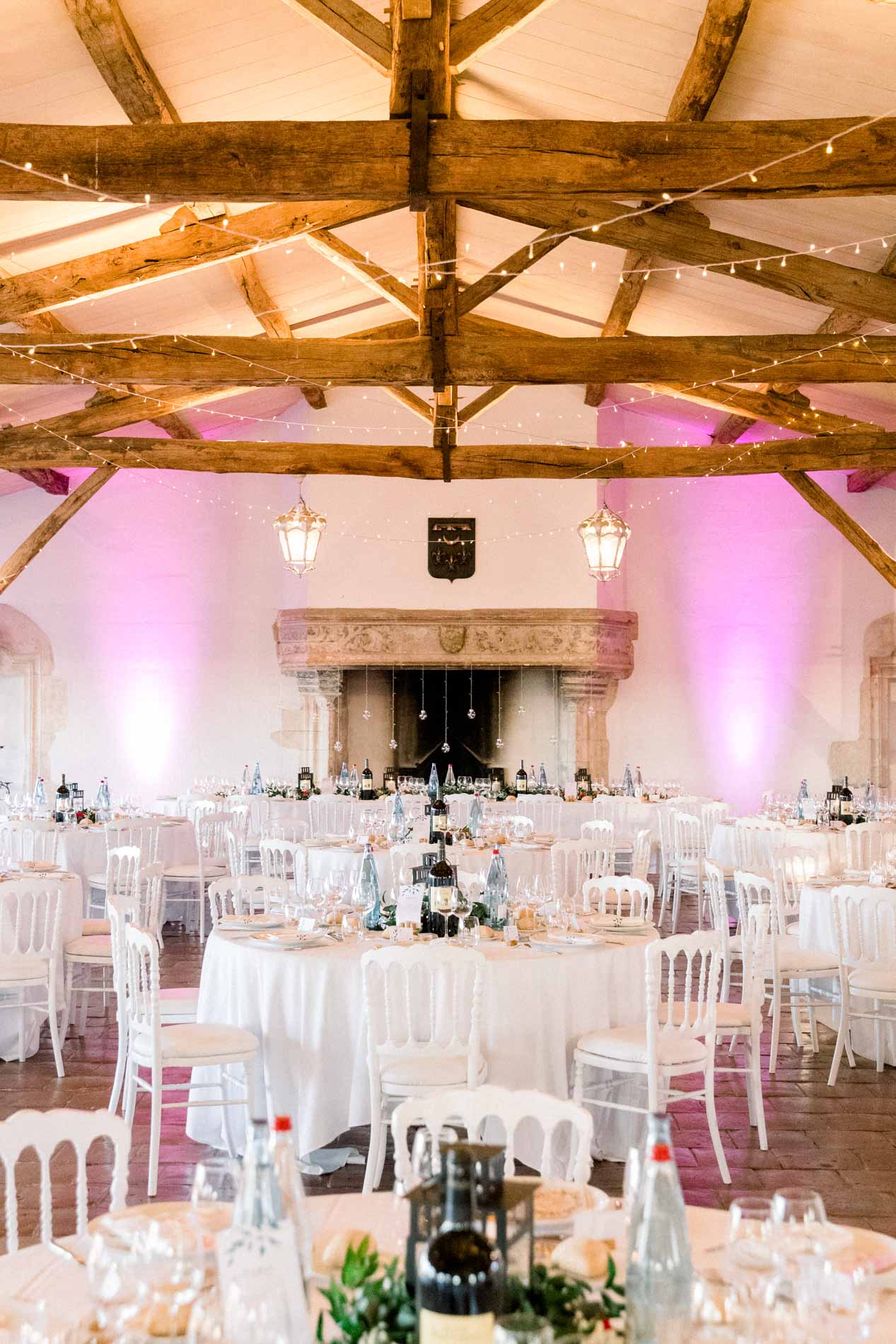Timber-beamed reception hall lit in pink before the wedding dinner