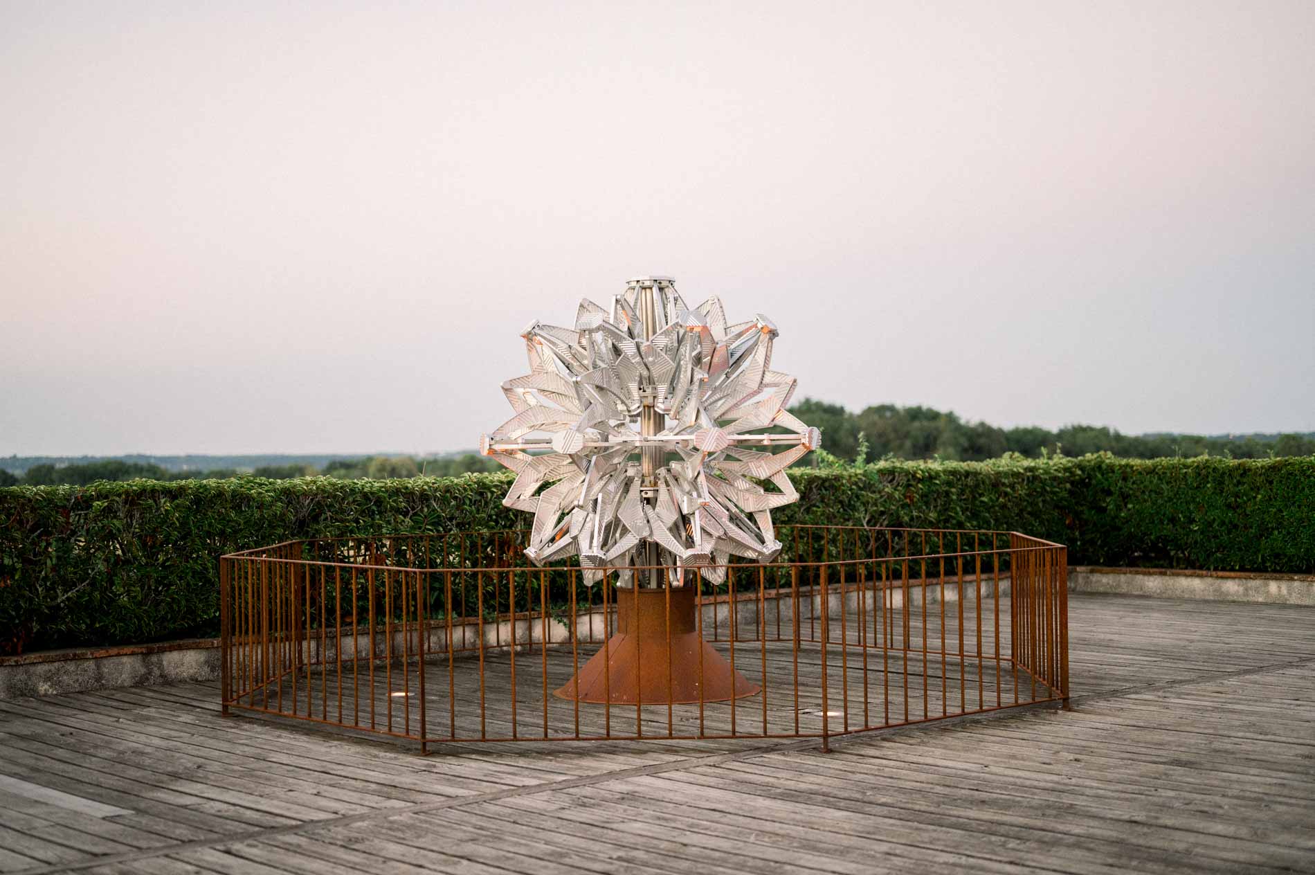 Metal sculpture on a wooden terrace at dusk, facing the vineyard