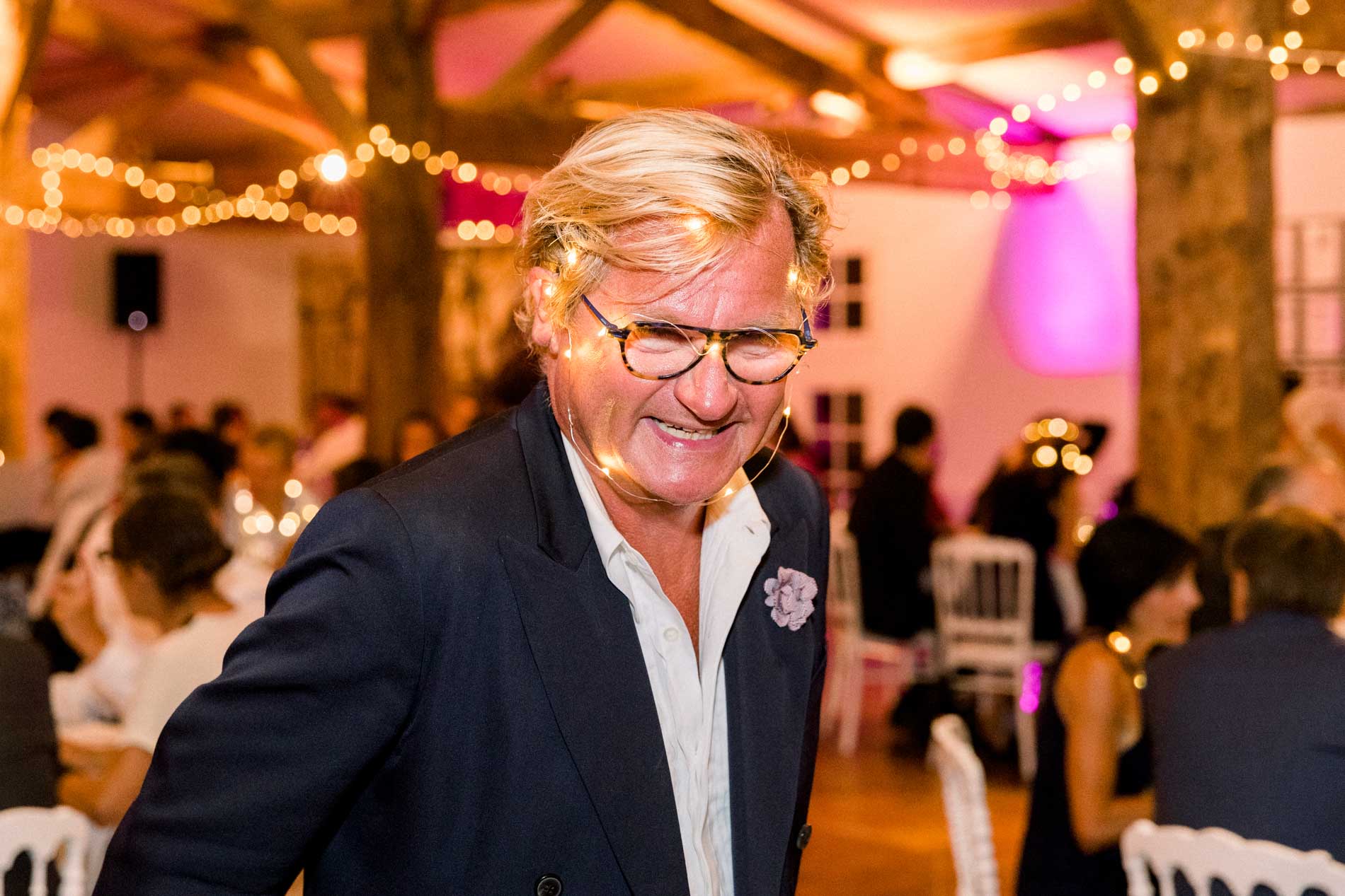 Guest in glasses laughing heartily during the wedding dinner