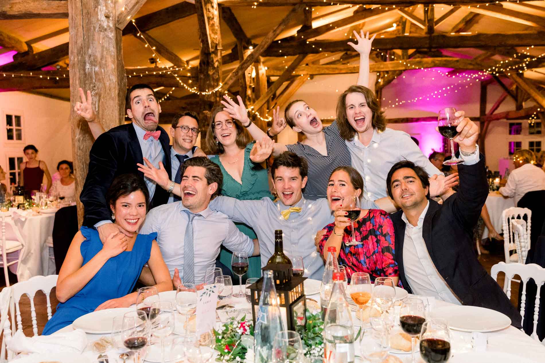 Table of guests striking playful poses during the wedding dinner