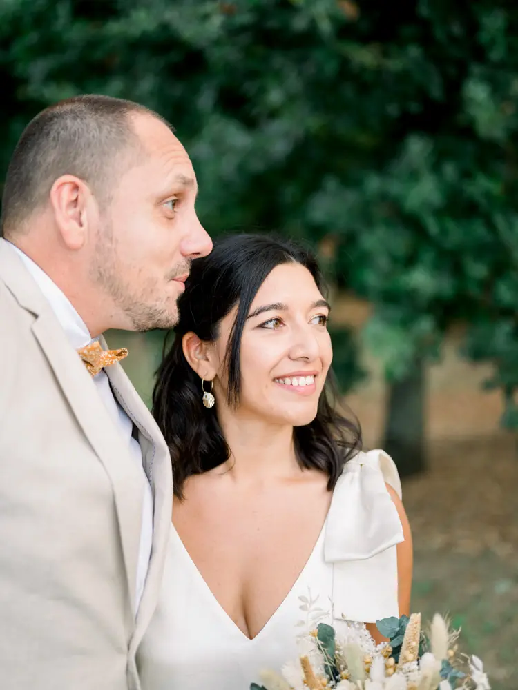 The smiling bride nestled against the groom in the Parc de Cazalet
