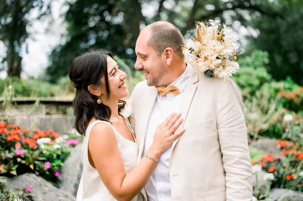 The bride laughing up at the groom before the flowers of the Parc de Cazalet