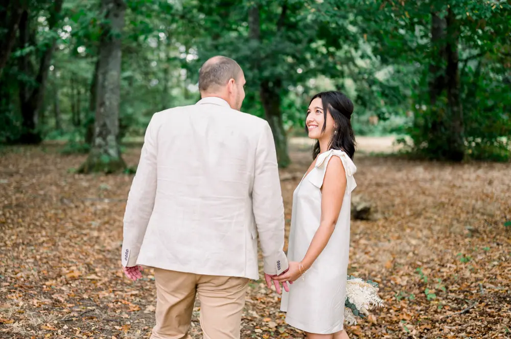 The couple hand in hand on a carpet of fallen leaves in the woods