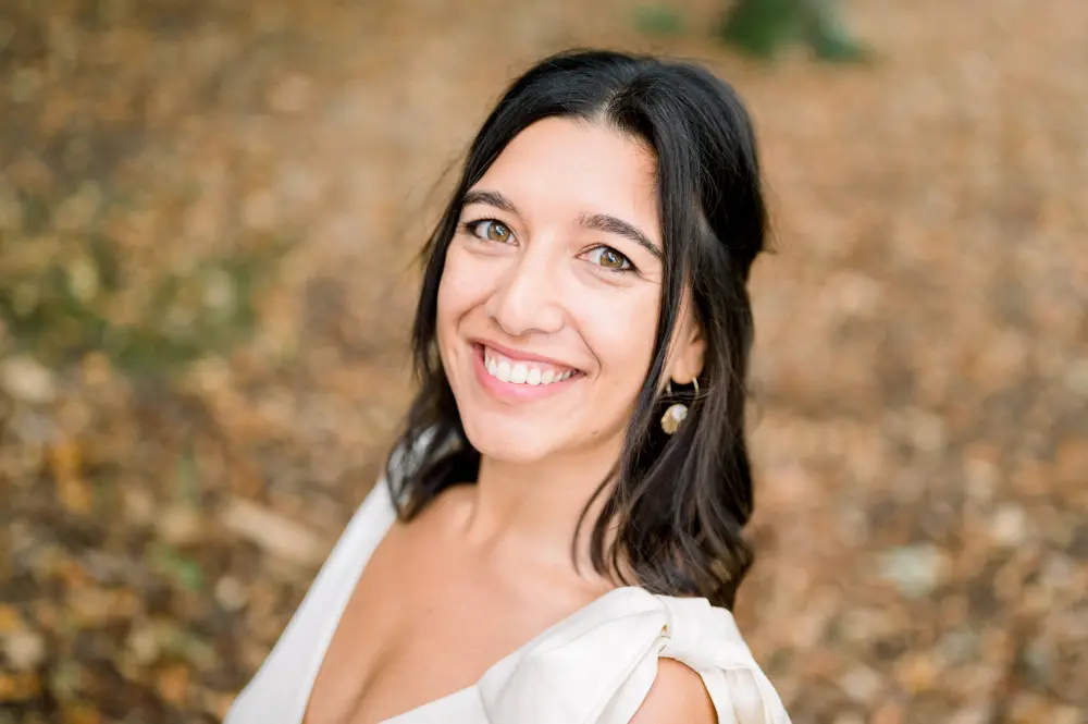 Portrait of the smiling dark-haired bride against autumn leaves