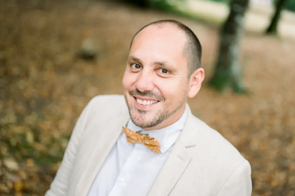 Portrait of the smiling groom in a linen jacket and mustard bow tie